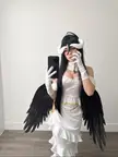 Jessie Rae as Albedo from Overlord in a white off-the-shoulder dress, black wings, and white horns mirror selfie