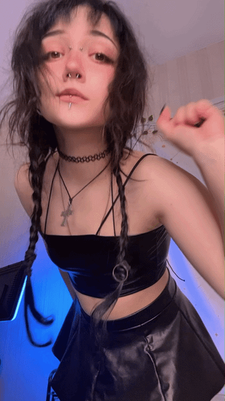 Slim white goth girl with braided brunette hair dancing in a black leather crop top and mini skirt