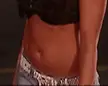 Candice Michelle wearing a black crop top and low-rise jeans with a studded belt, showing her skinny abs.