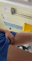 Slim brunette in blue scrubs masturbating and touching her mouth in a medical room