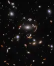 This is a spectacular example of gravitational lensing, a phenomenon which occurs when a massive celestial object such as a galaxy cluster deforms spacetime and causes the path of light from more distant galaxies to be deflected, almost as if a monumental lens was redirecting it.