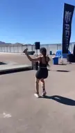 Camila Cabello in a black sports bra and bike shorts dancing in a sunny outdoor area