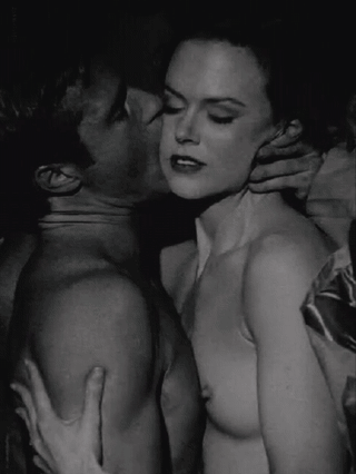 Nicole Kidman and a muscular man naked, kissing and touching breasts in a bedroom scene from Eyes Wide Shut
