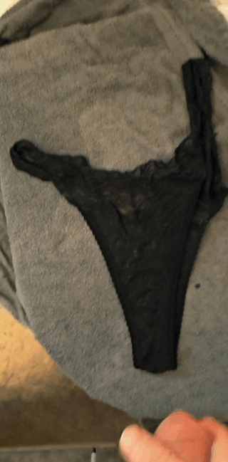 Hyperspermia cumshot of a white man ejaculating on black panties on a grey towel.