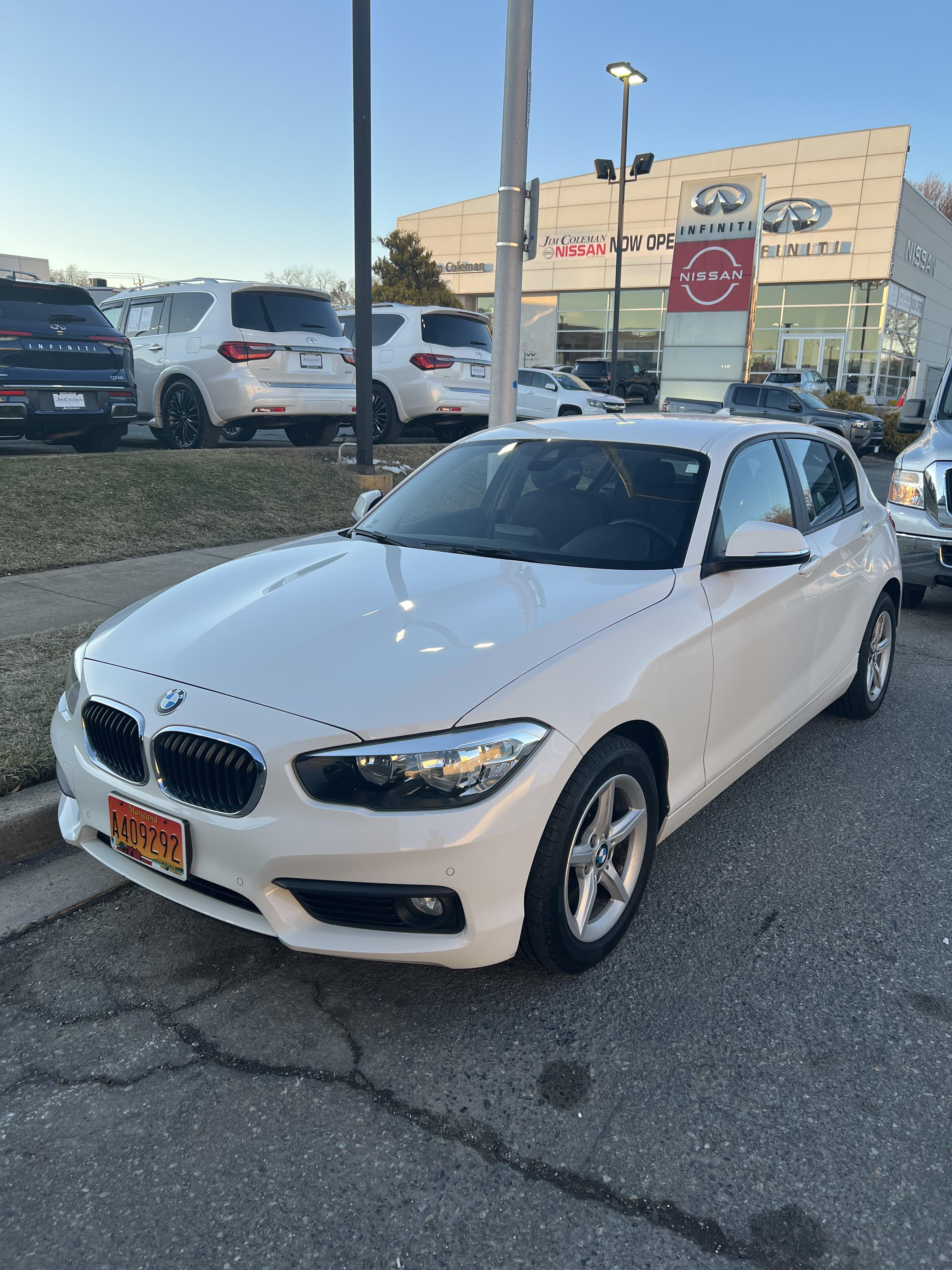 Front and back view of a white BMW hatchback parked on a street near buildings.