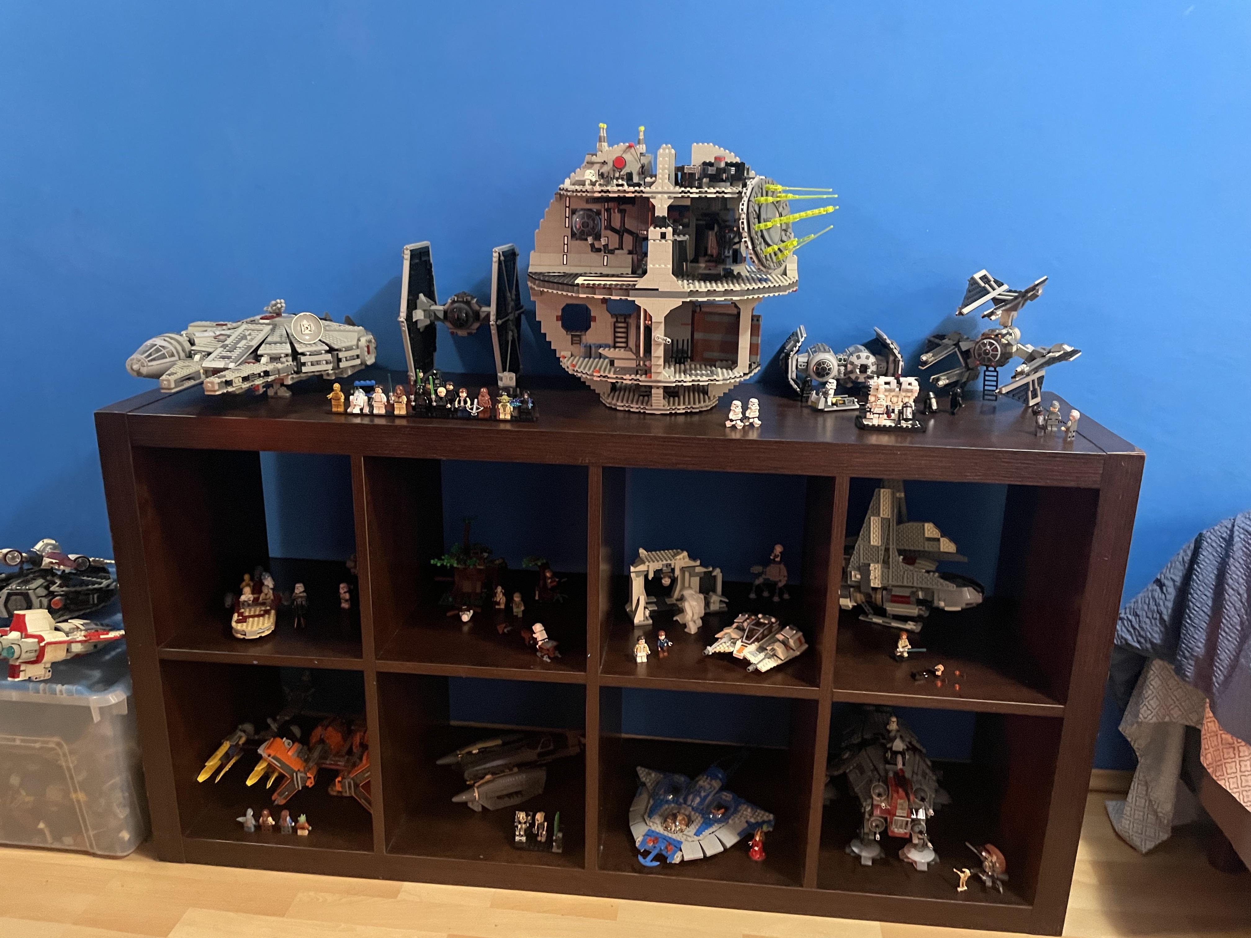 LEGO building set with minifigures and a large brown creature on a wooden shelf against a blue wall