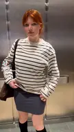 levi_coralynn in a tight grey mini dress and black knee-high socks posing in an elevator