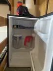 An open mini-fridge in a college dorm containing two water pitchers and a blue cloth.
