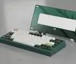 A dark green Doom75 mechanical keyboard with white and beige keycaps in front of a green glass panel.