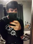 A trans woman with brown hair and red nails taking a mirror selfie in a black graphic sweatshirt.