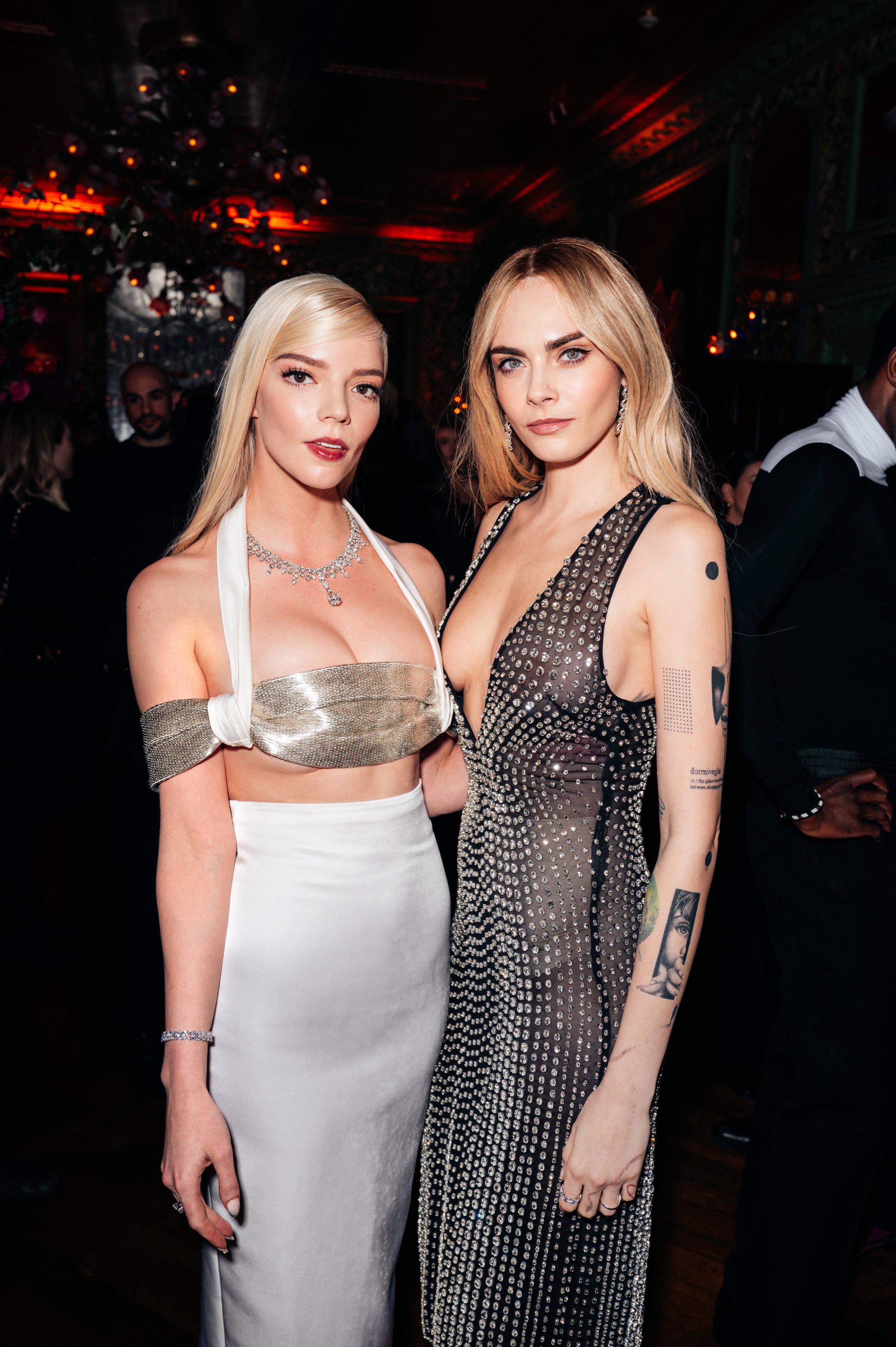 Interracial duo of a slim latina woman in a white crop top and a slim blonde white woman in a grey sweater.