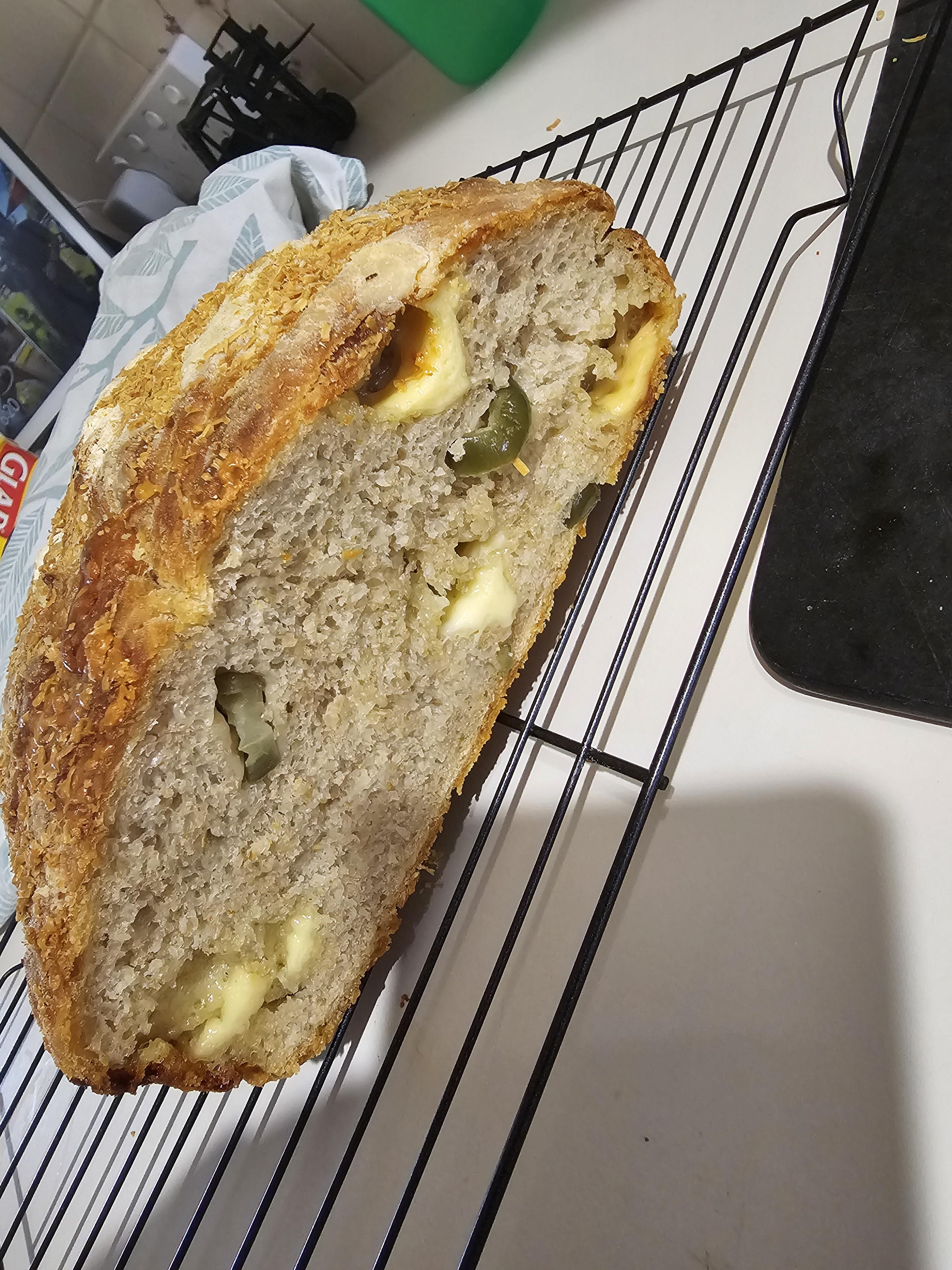 Jalapeno and cheese loaf of homemade bread being baked, cooled on a rack, and sliced by a hand with pale skin