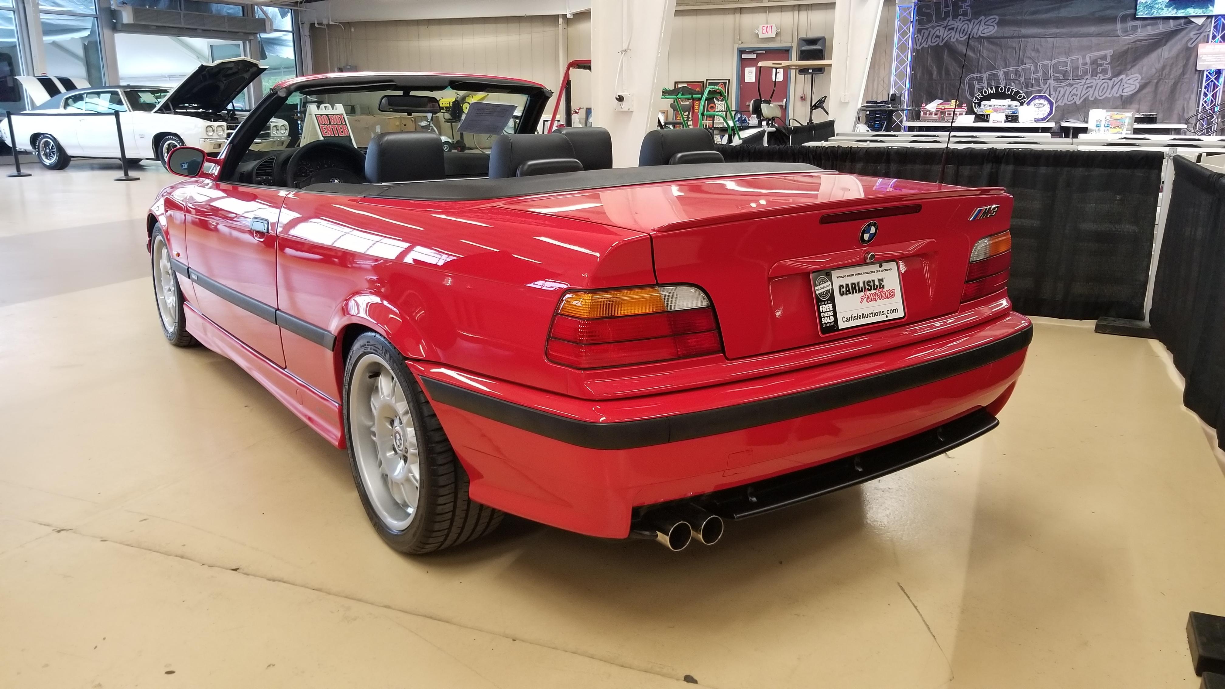 Red BMW E36 M3 cabrio in an indoor showroom, including a close-up of the M3 badge.
