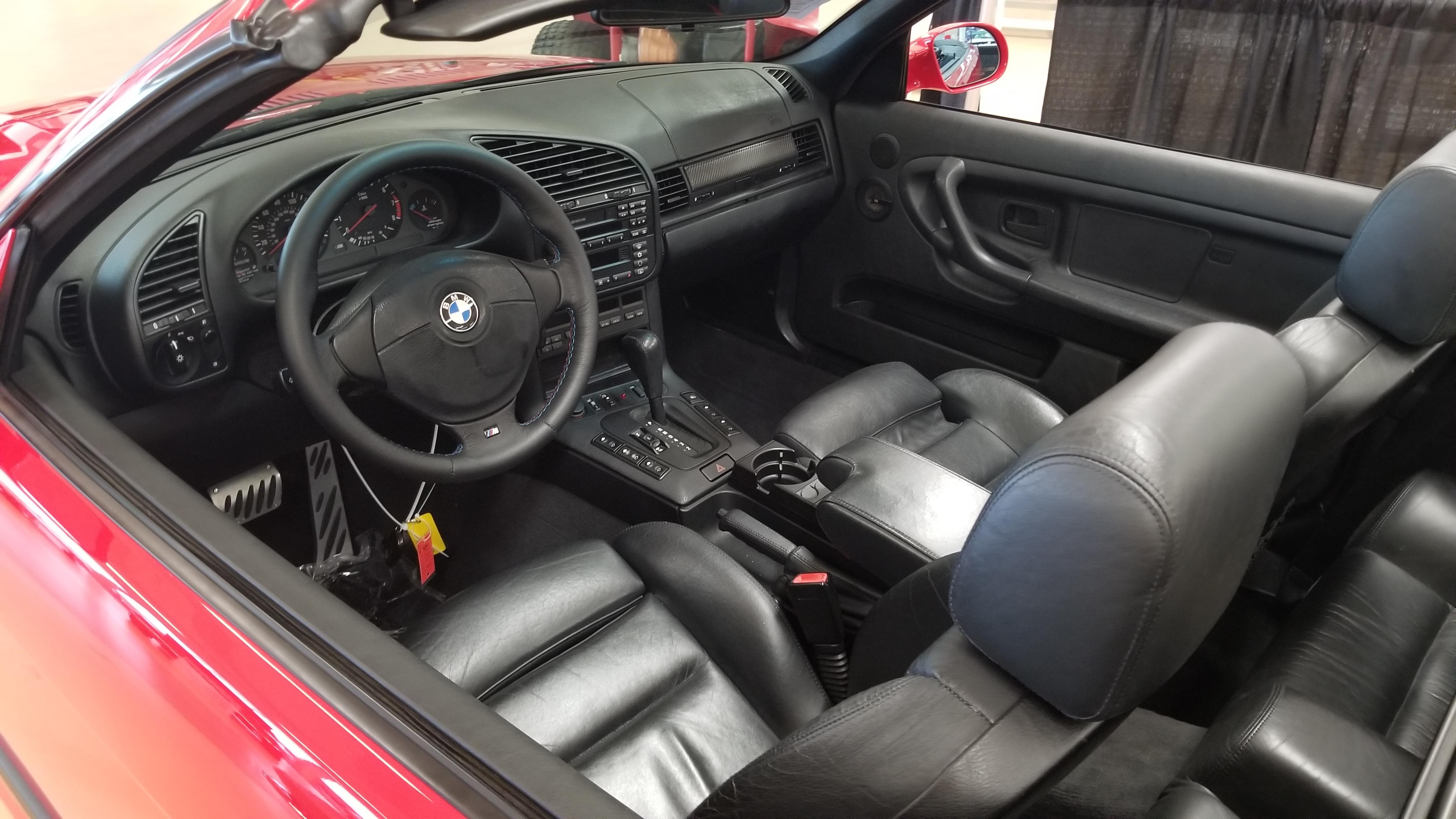 Red BMW E36 M3 cabrio in an indoor showroom, including a close-up of the M3 badge.