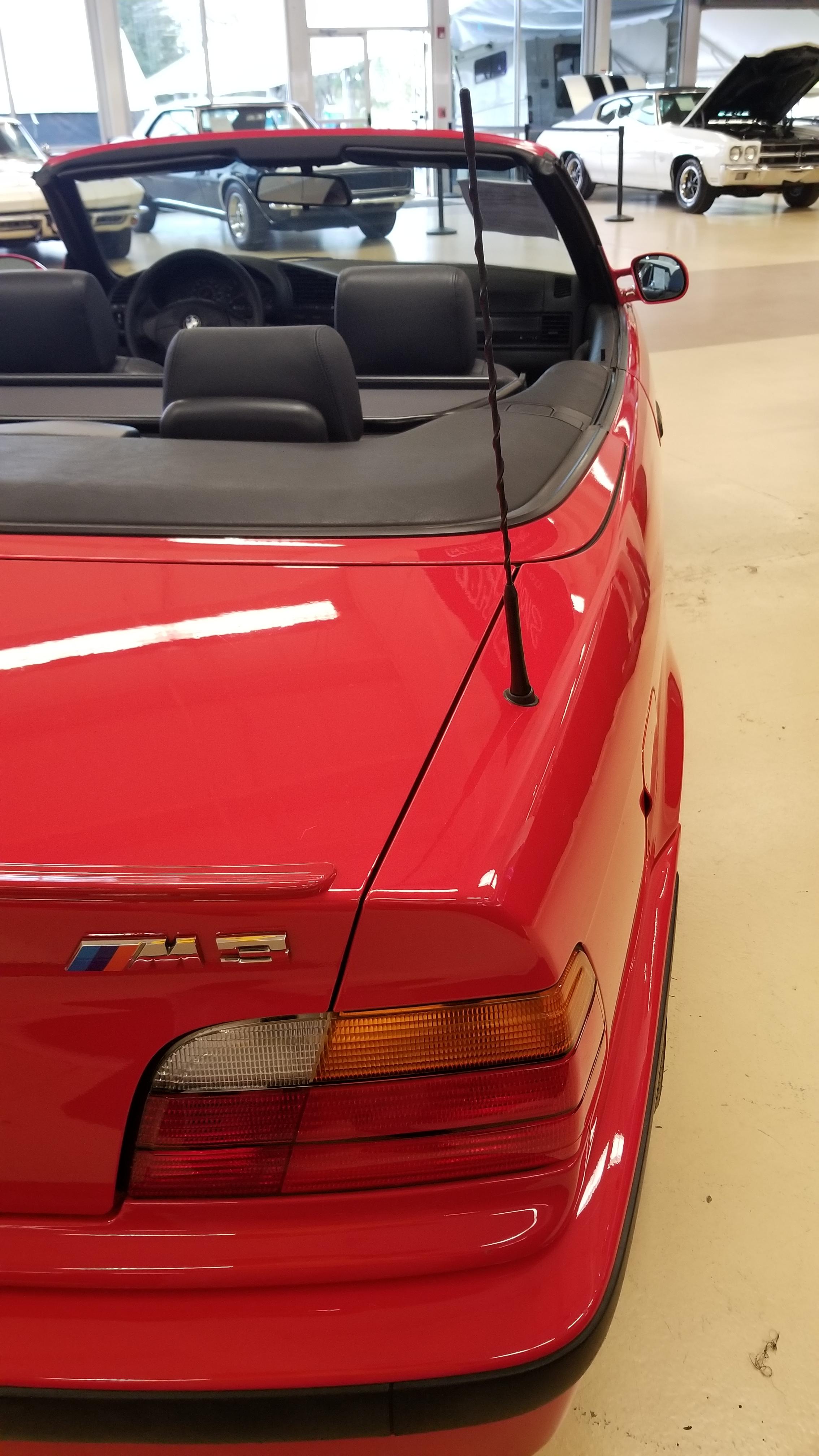 Red BMW E36 M3 cabrio in an indoor showroom, including a close-up of the M3 badge.