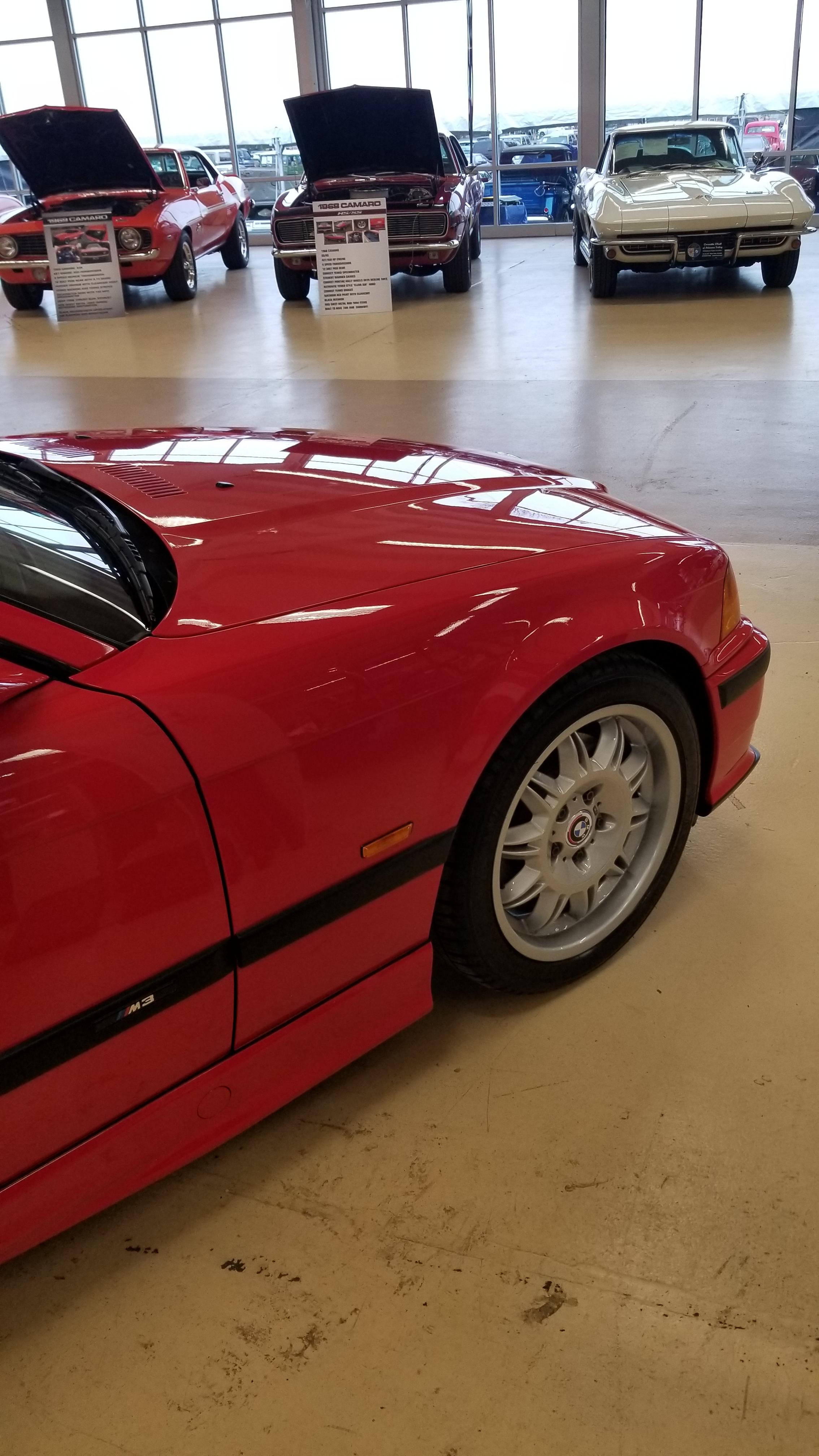 Red BMW E36 M3 cabrio in an indoor showroom, including a close-up of the M3 badge.