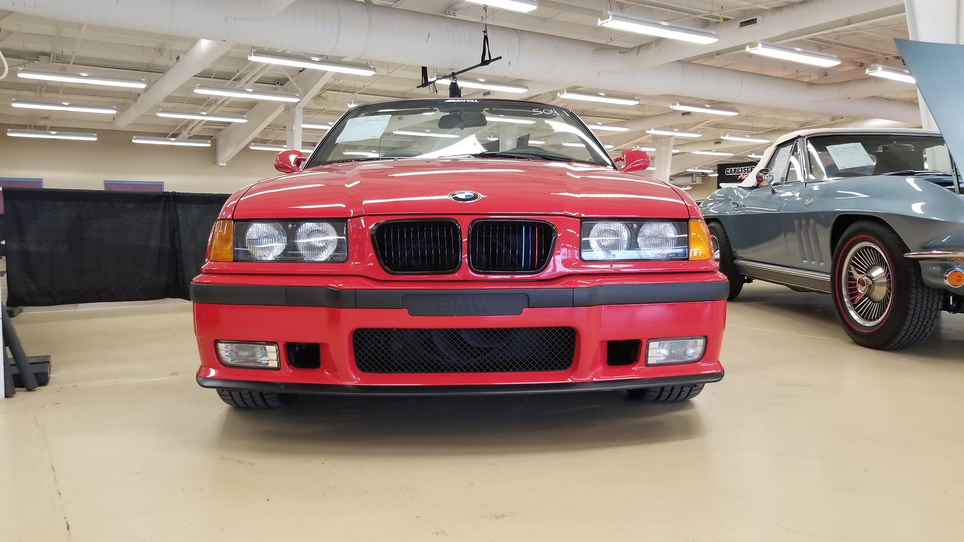Red BMW E36 M3 cabrio in an indoor showroom, including a close-up of the M3 badge.