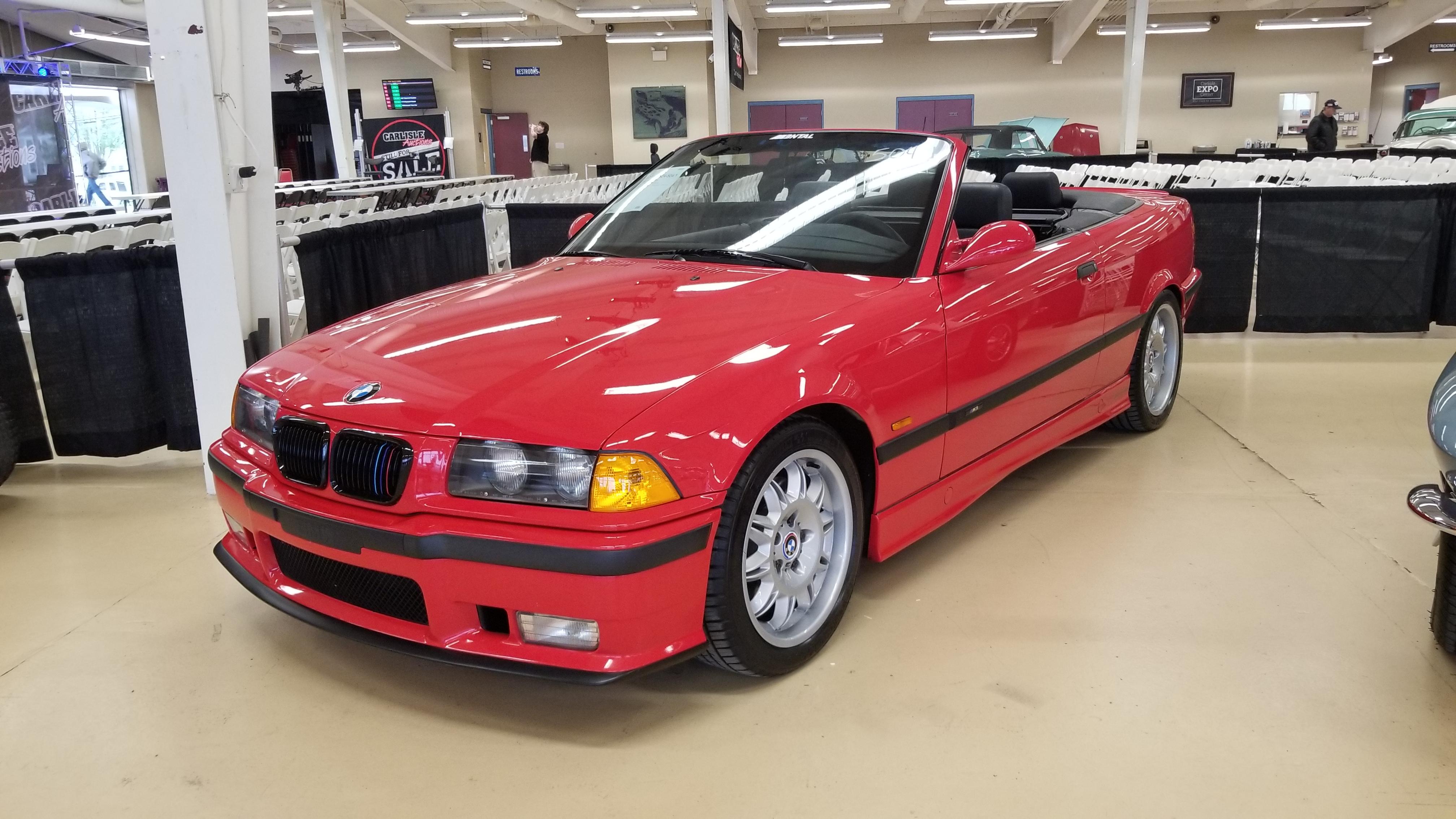 Red BMW E36 M3 cabrio in an indoor showroom, including a close-up of the M3 badge.