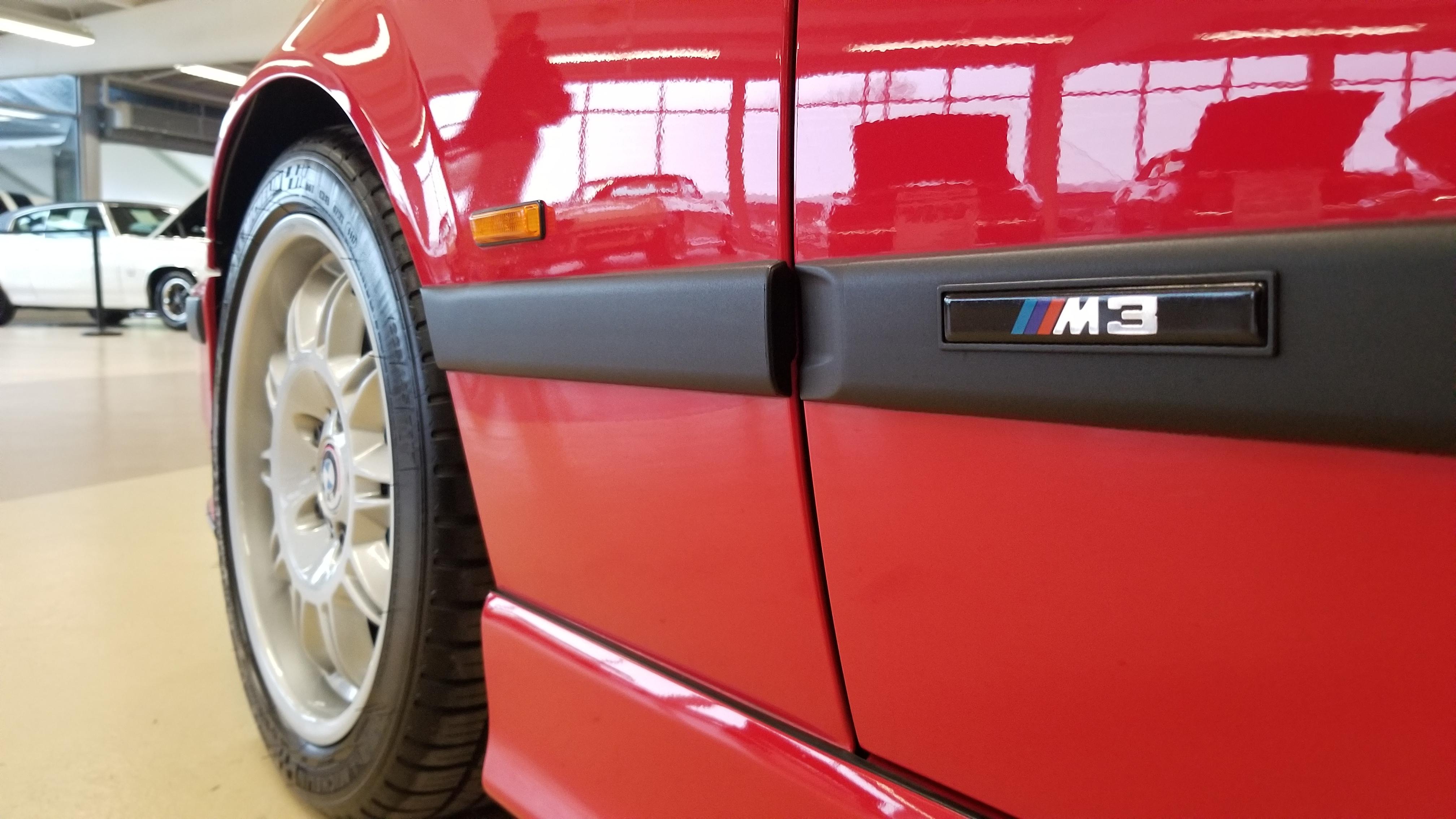 Red BMW E36 M3 cabrio in an indoor showroom, including a close-up of the M3 badge.