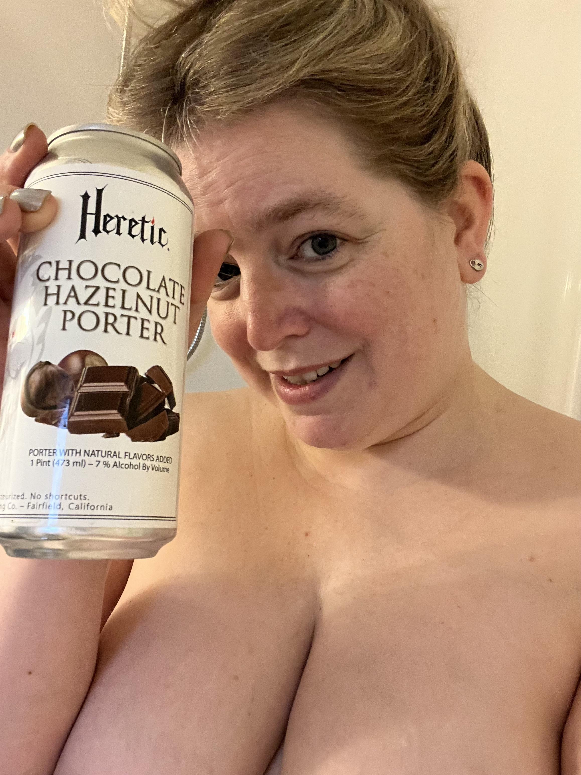 Busty blonde woman taking a shower beer in a bubble bath with a Nintendo Switch and Heretic Chocolate Hazelnut Porter