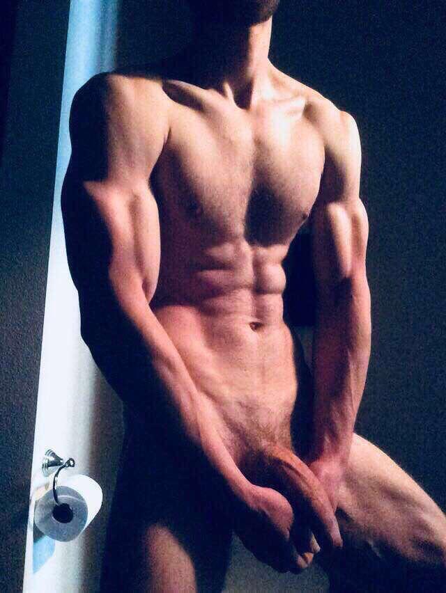 Muscular white man with a massive cock posing for a shirtless mirror selfie in a bathroom wearing black underwear