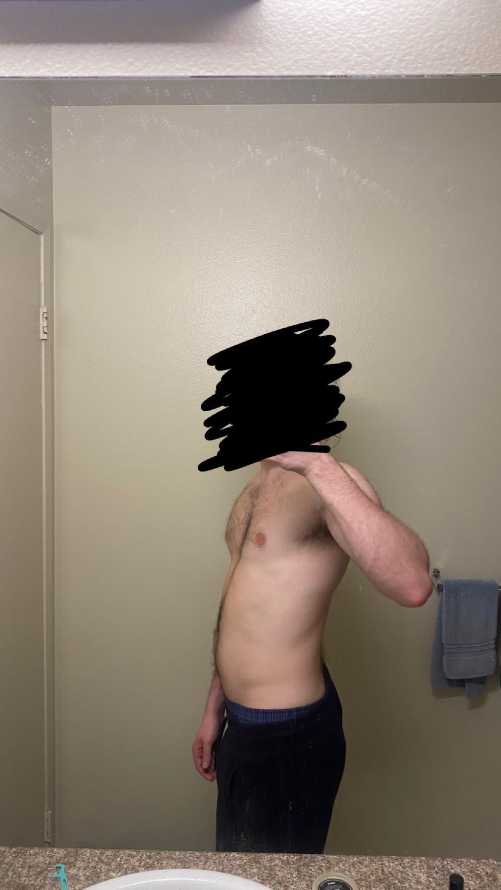 Shirtless white man in blue shorts posing for mirror selfies to show his bodybuilding physique in a bathroom