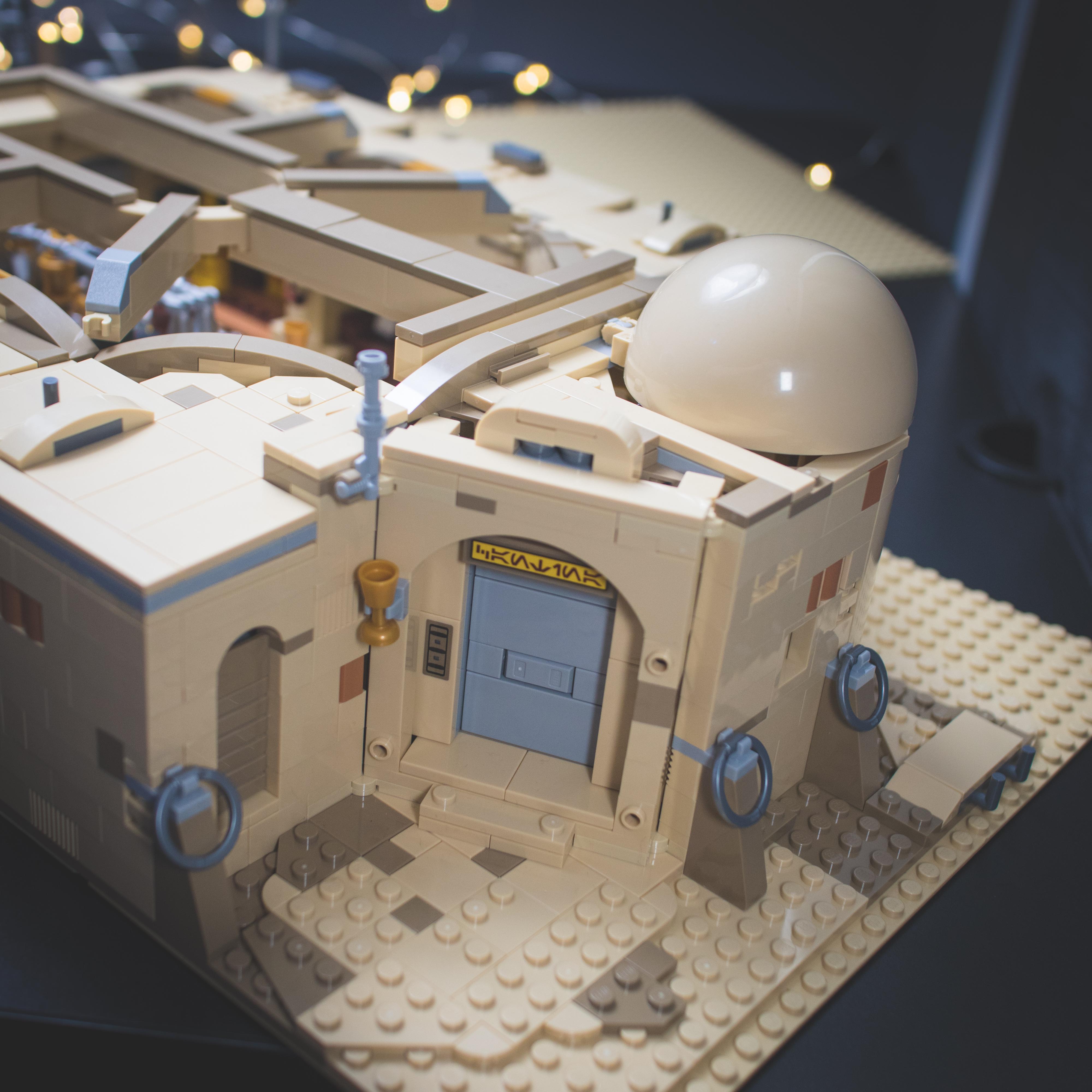 LEGO Star Wars minifigures and buildings in a Mos Eisley Cantina desert scene with a pirate flag and spaceship