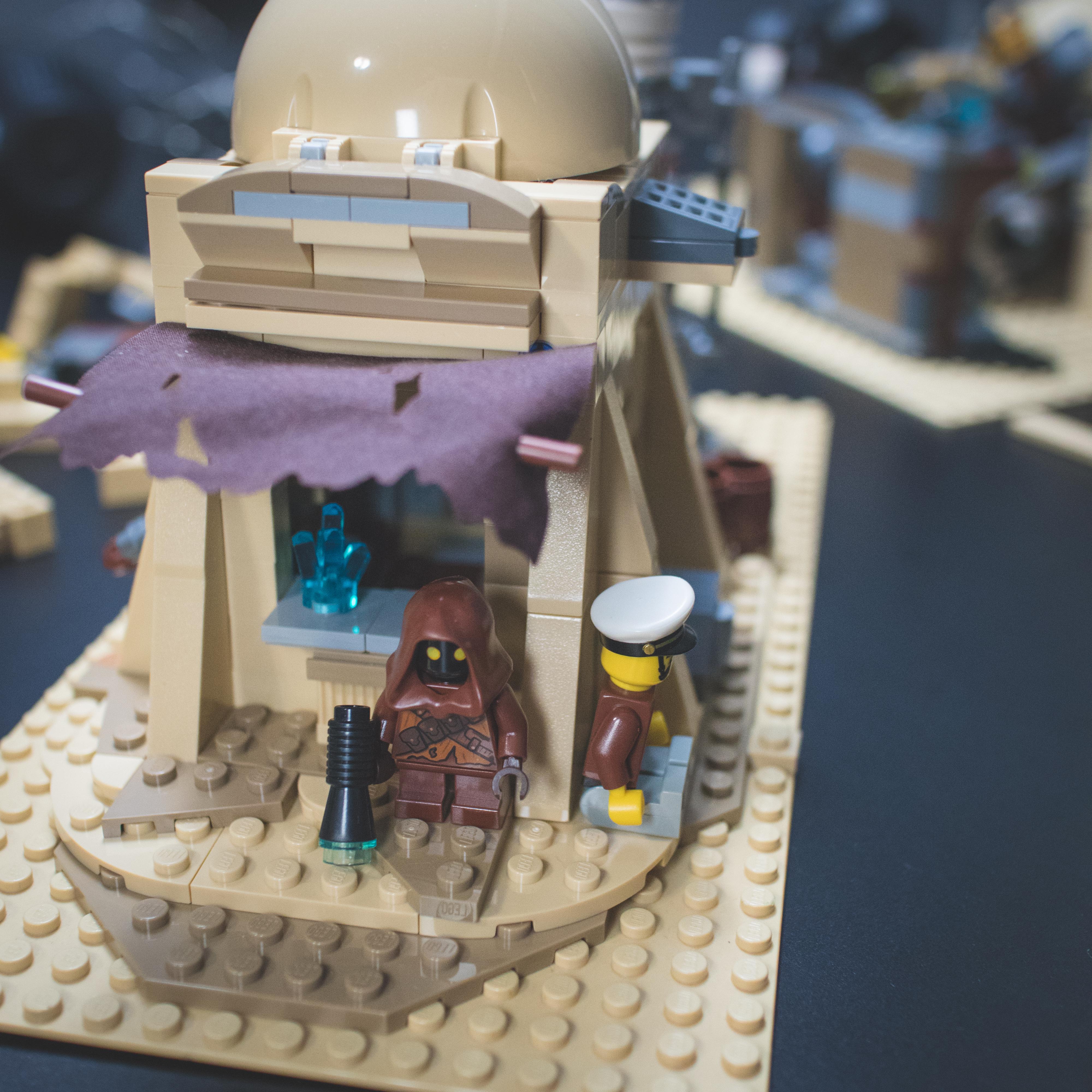 LEGO Star Wars minifigures and buildings in a Mos Eisley Cantina desert scene with a pirate flag and spaceship