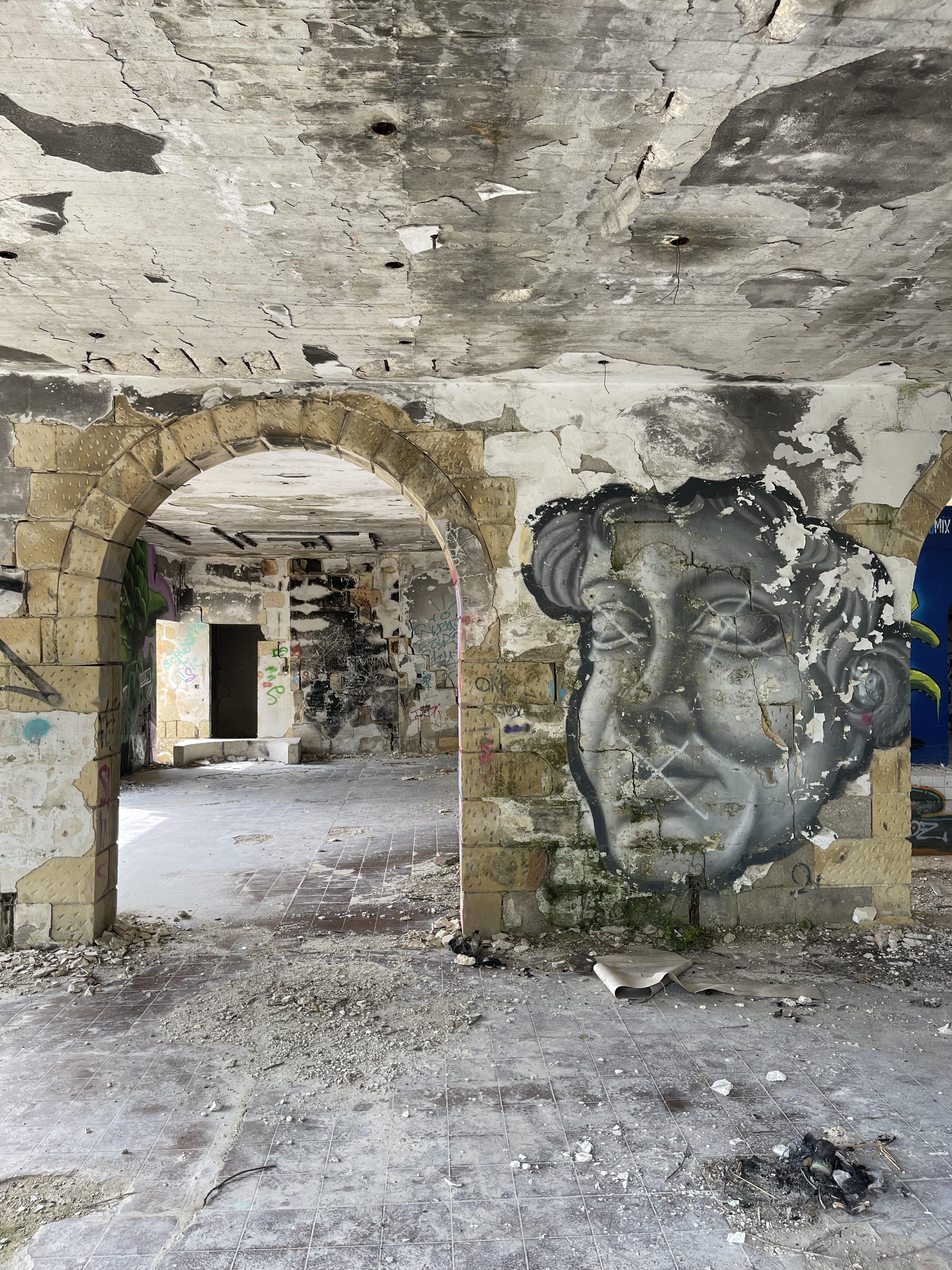 Urban exploration of a derelict 5 storey concrete building in Malta with graffiti and rubble.
