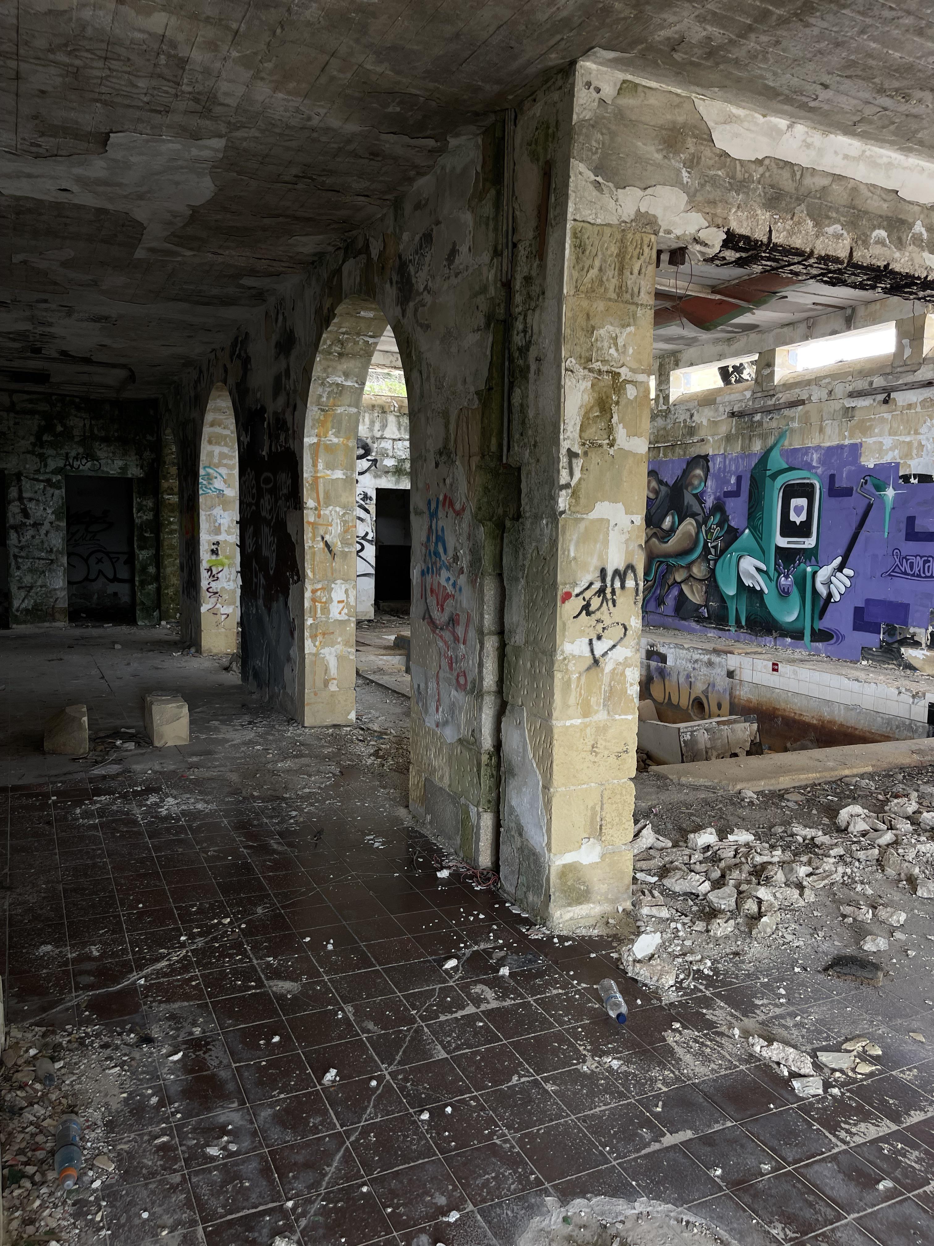Urban exploration of a derelict 5 storey concrete building in Malta with graffiti and rubble.