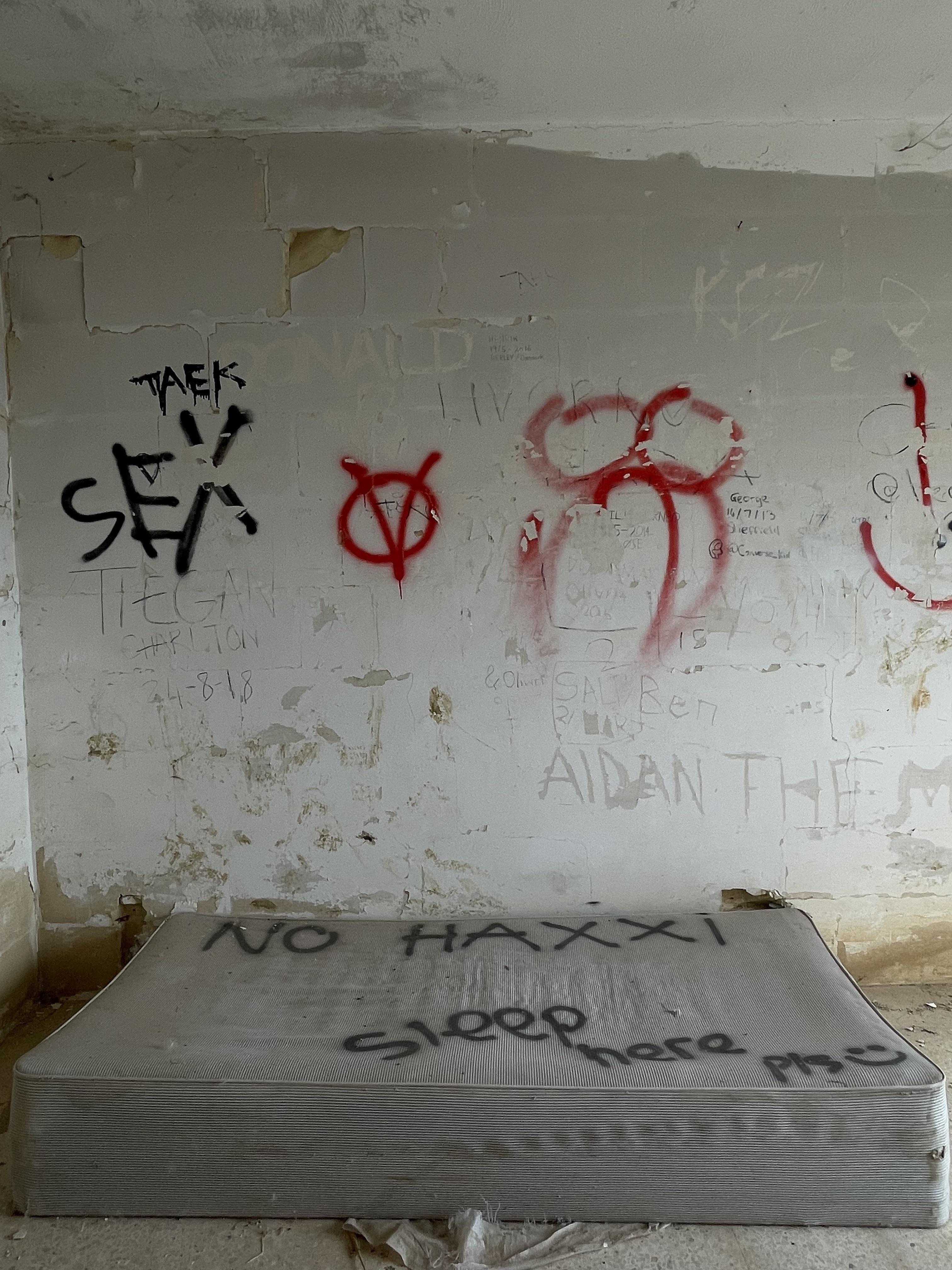 Urban exploration of a derelict 5 storey concrete building in Malta with graffiti and rubble.