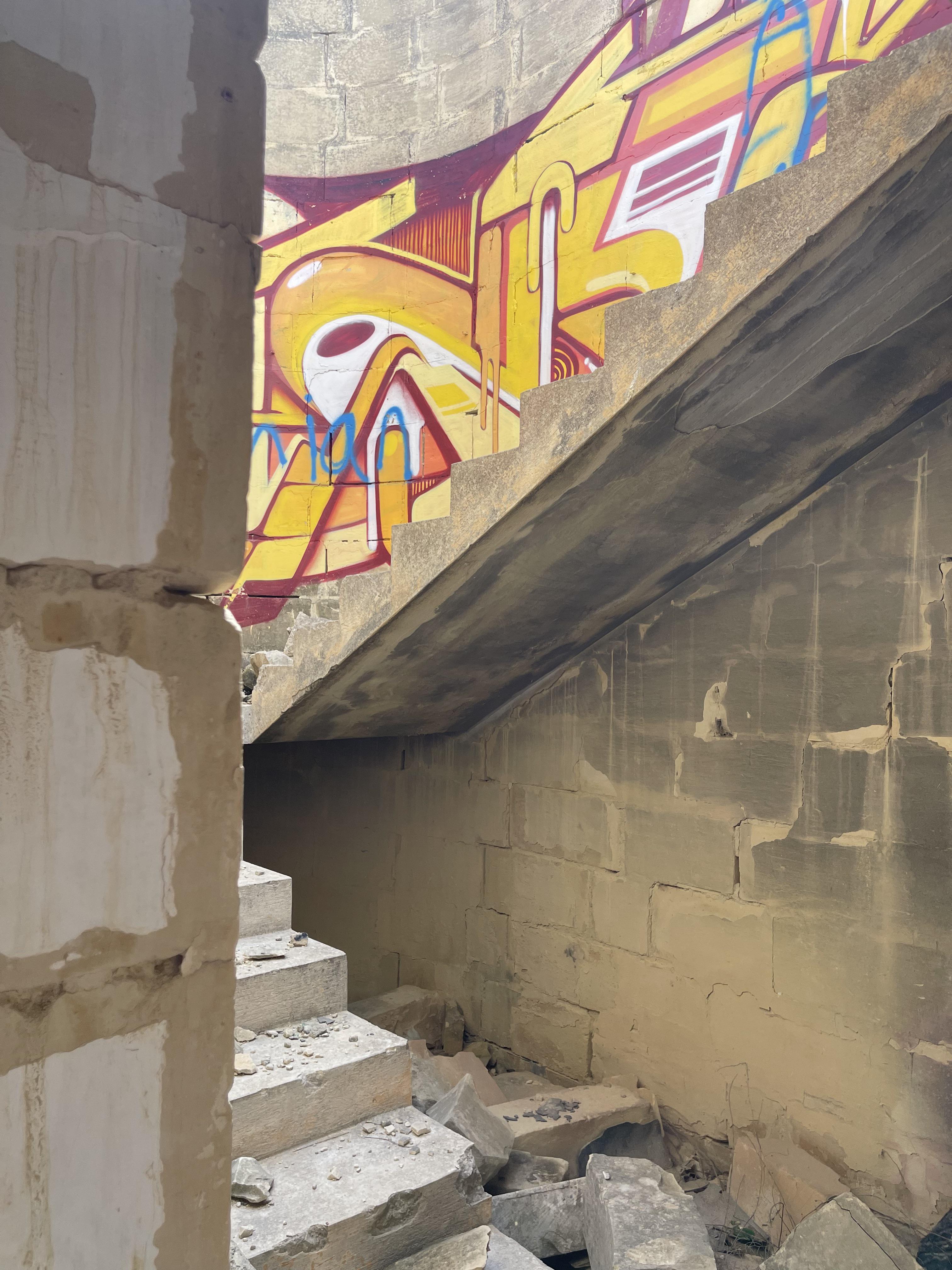Urban exploration of a derelict 5 storey concrete building in Malta with graffiti and rubble.