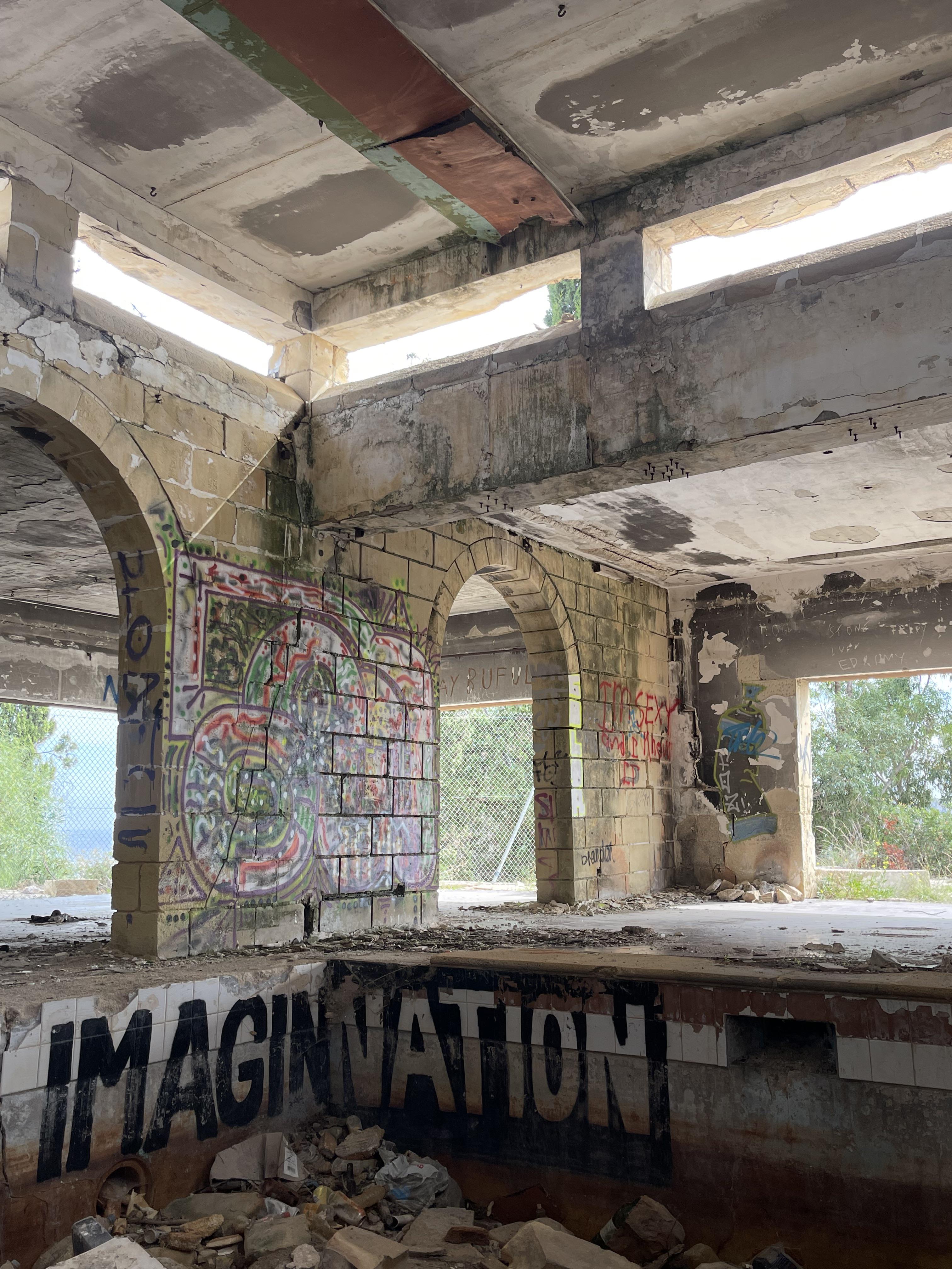 Urban exploration of a derelict 5 storey concrete building in Malta with graffiti and rubble.