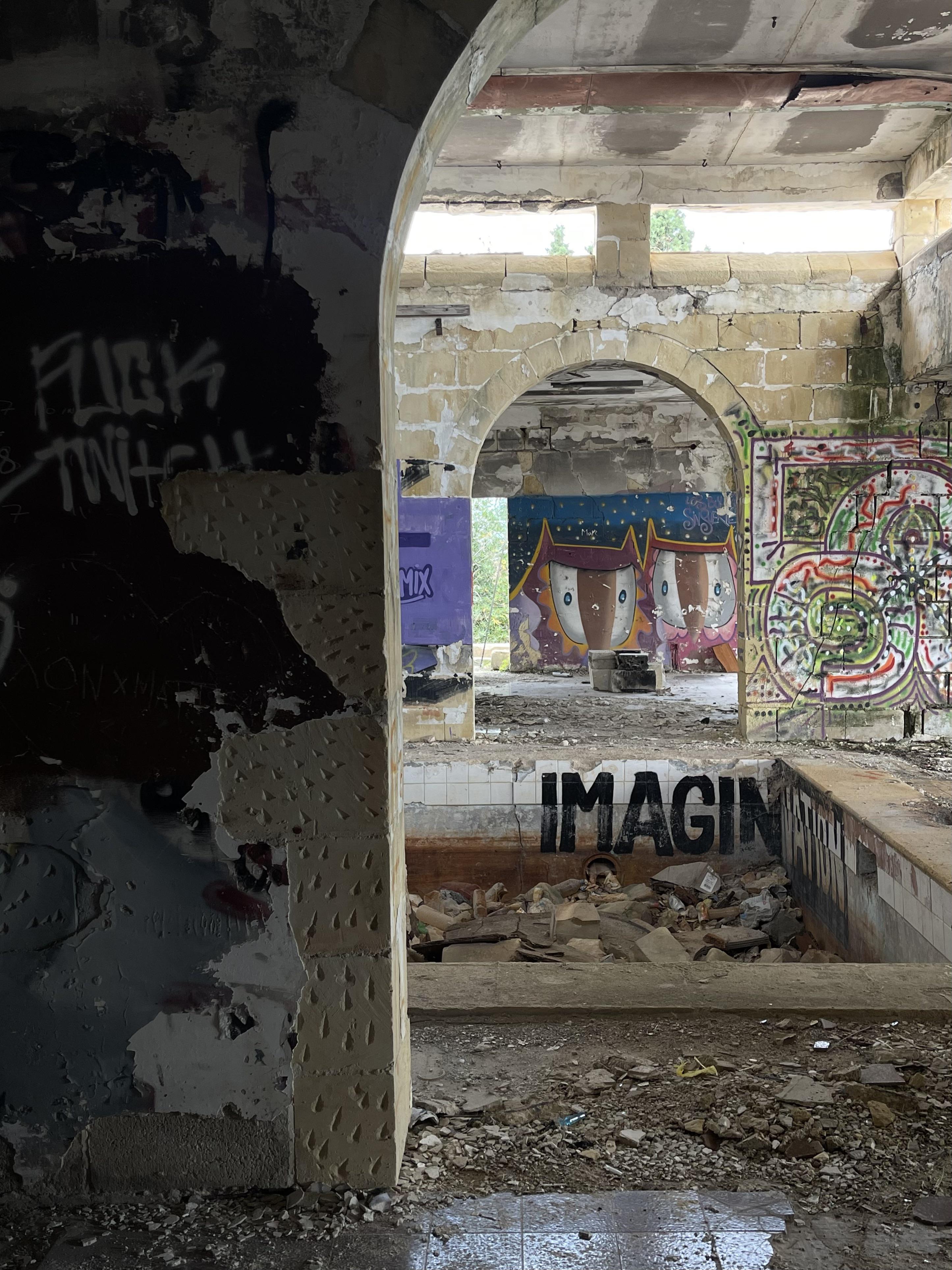 Urban exploration of a derelict 5 storey concrete building in Malta with graffiti and rubble.