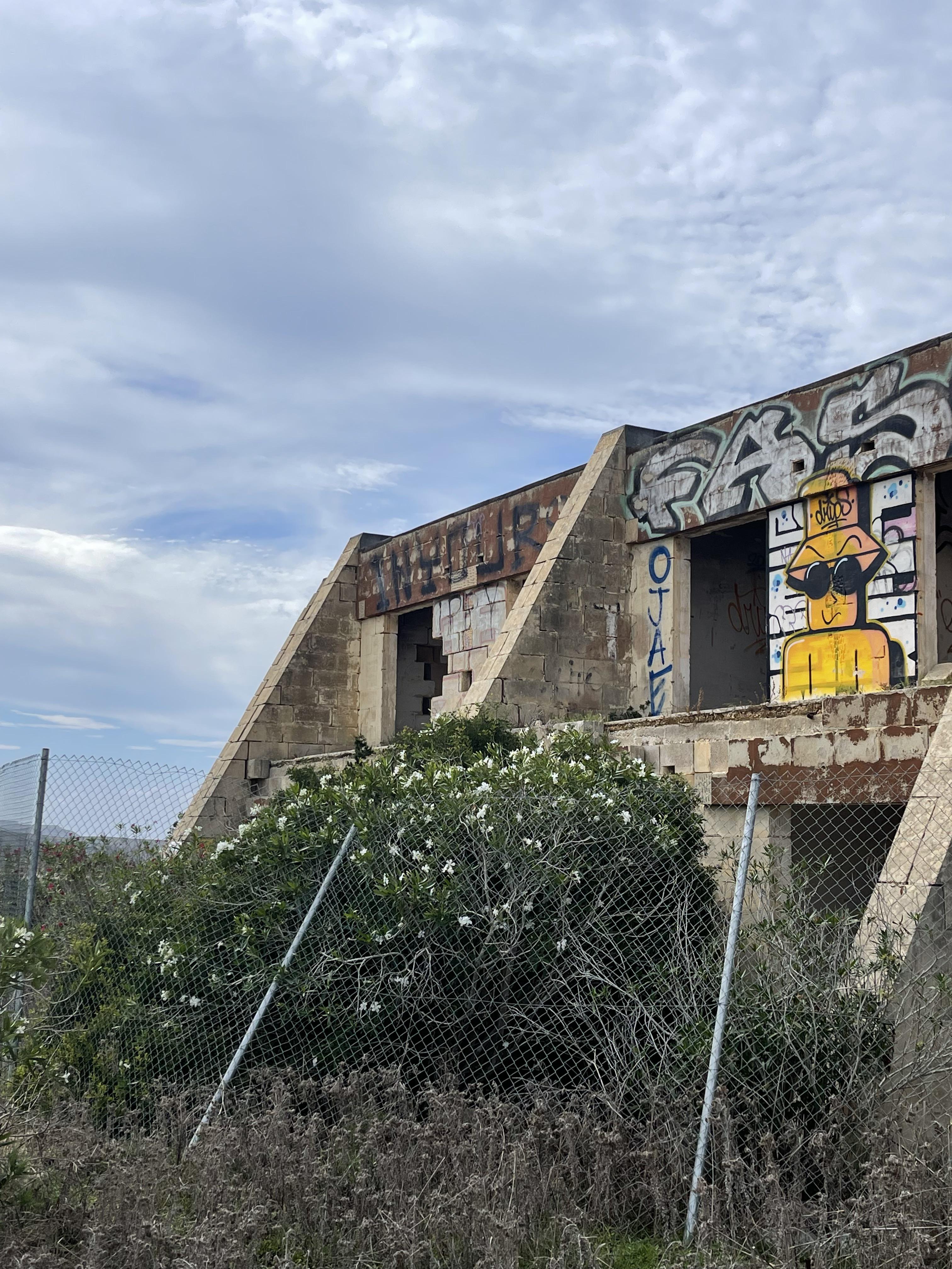 Urban exploration of a derelict 5 storey concrete building in Malta with graffiti and rubble.
