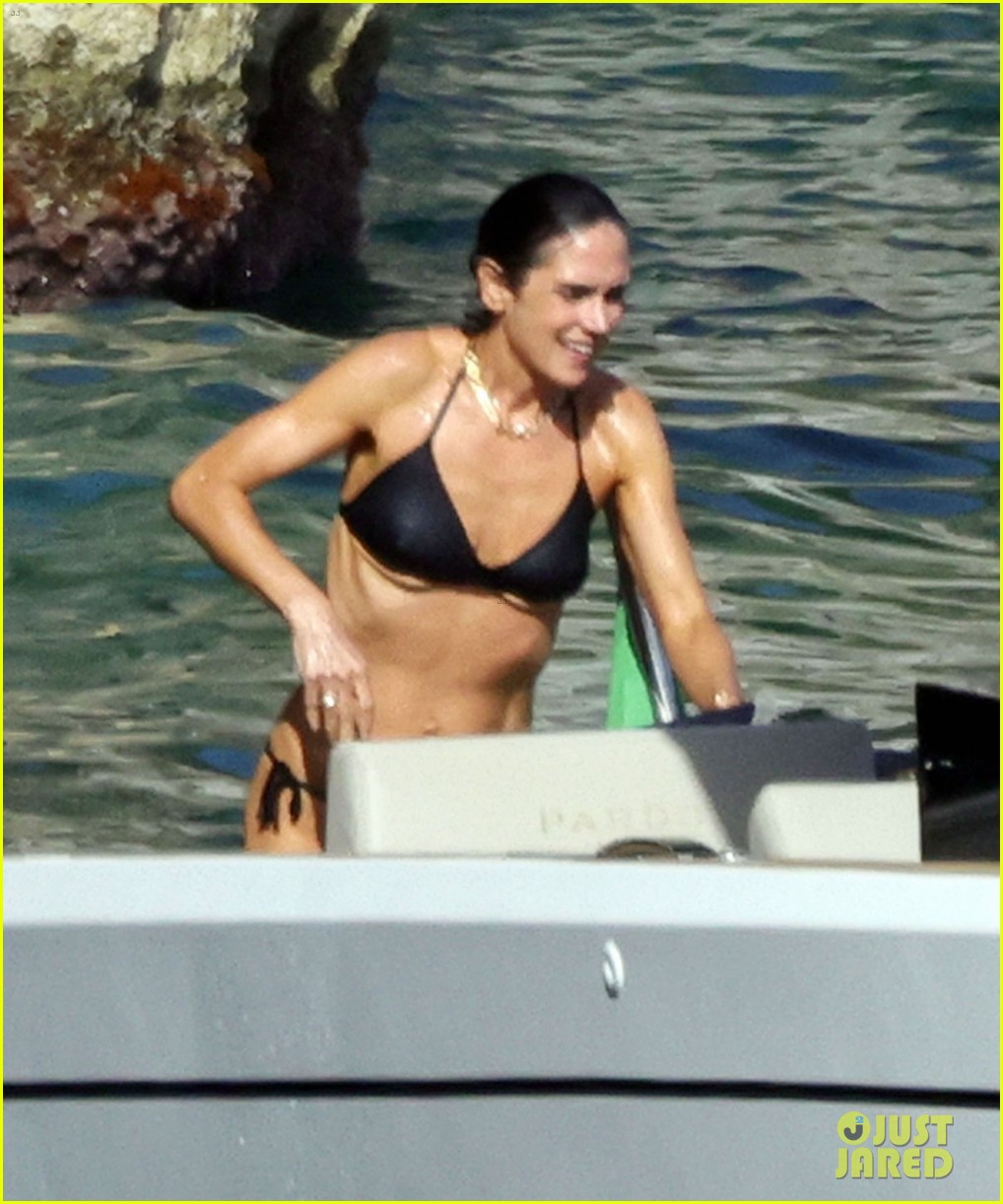 Muscled Jennifer Connelly in a black bikini swimming and climbing onto a boat in the ocean