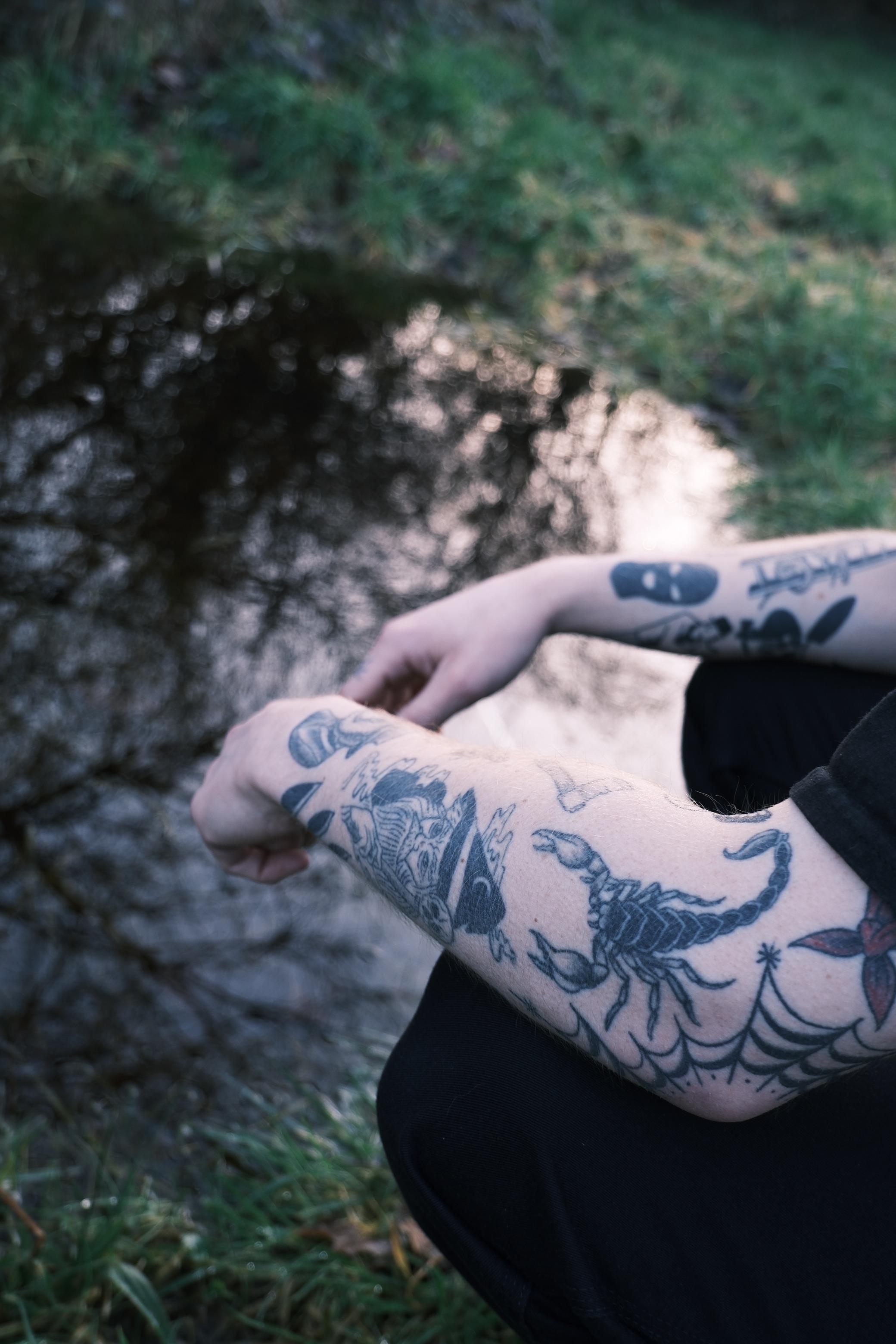 Moody Fujifilm X-M5 shots of a person with a tattoo sleeve, a city street at night, and a houseplant by a window.