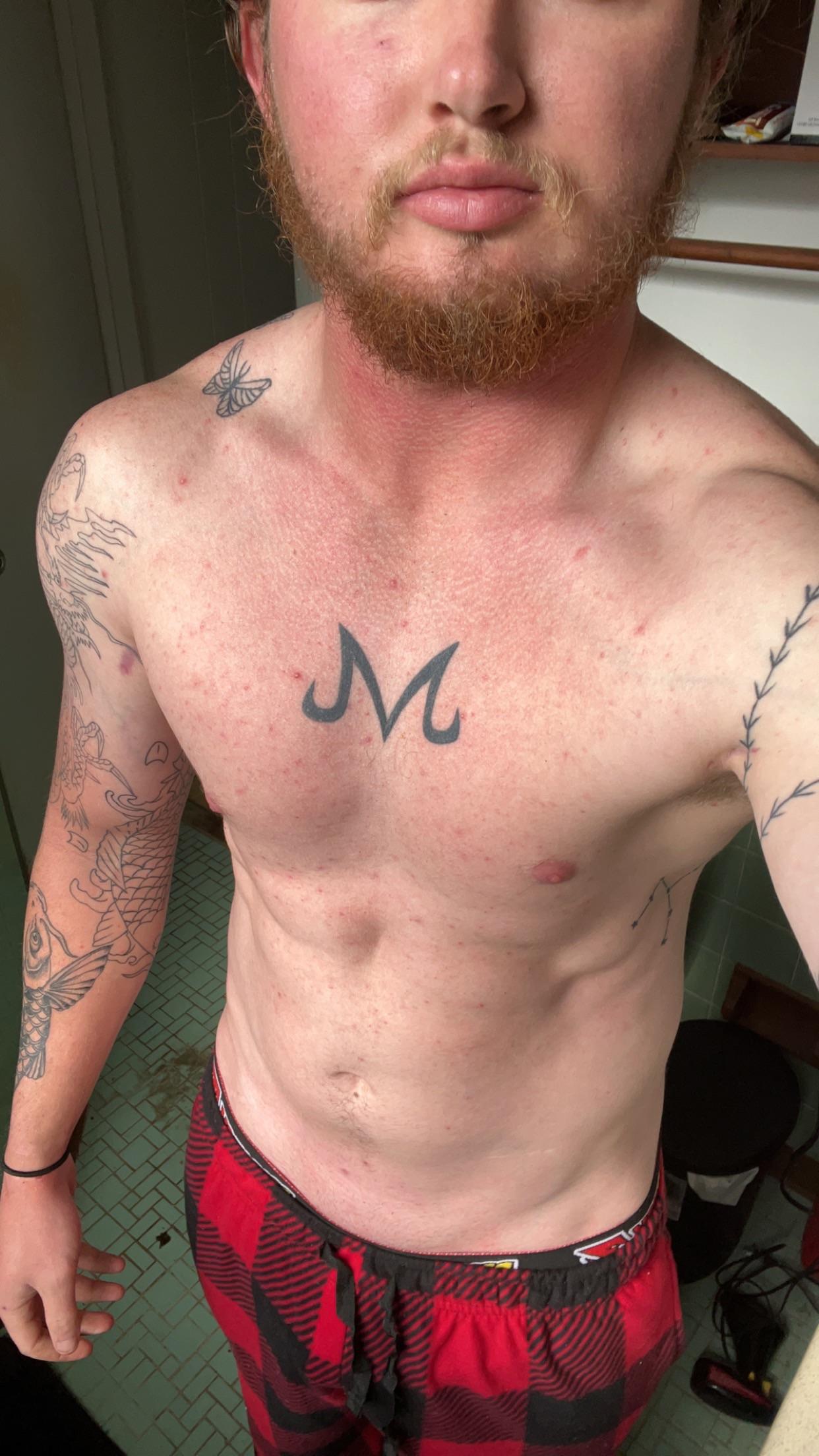 Athletic white man with a red beard and tattoos posing in red plaid boxers.