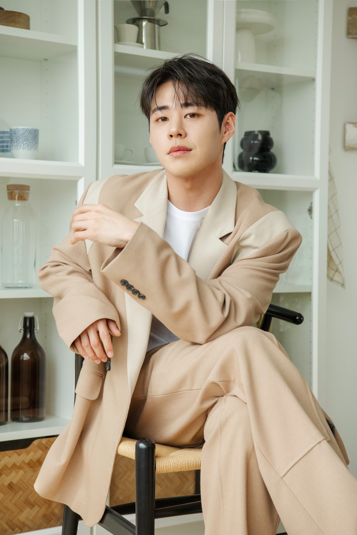 IMFACT Taeho in a beige suit, light blue sweater, and ripped denim jeans