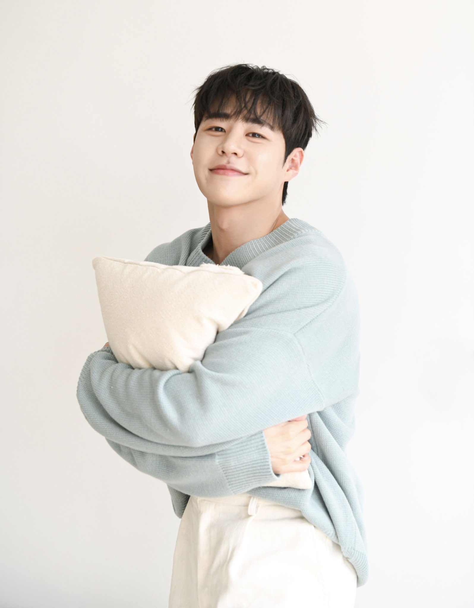 IMFACT Taeho in a beige suit, light blue sweater, and ripped denim jeans