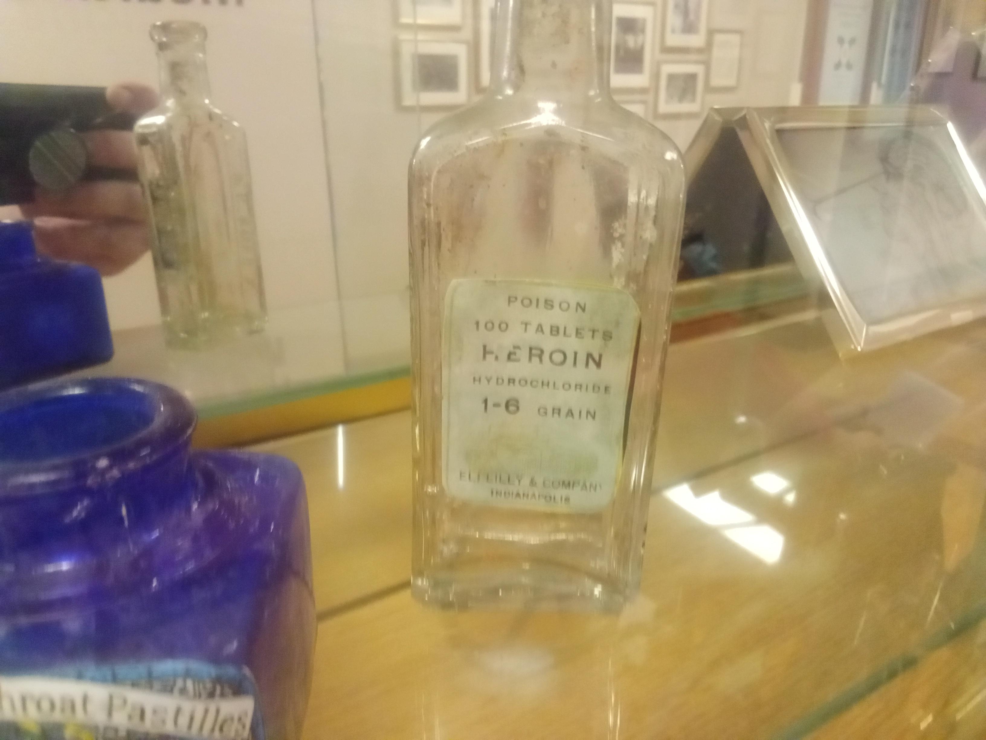 Vintage pharmaceutical heroin bottles and tablets in a museum display case