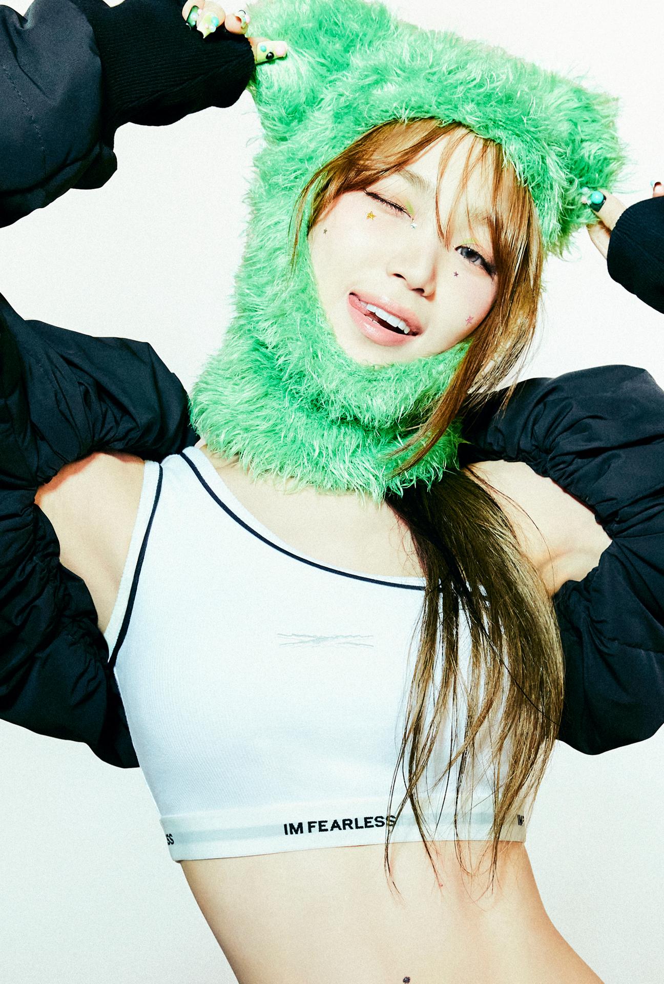 LE SSERAFIM member in a green fuzzy hood, white bralette, and black jacket posing for EASY concept photos