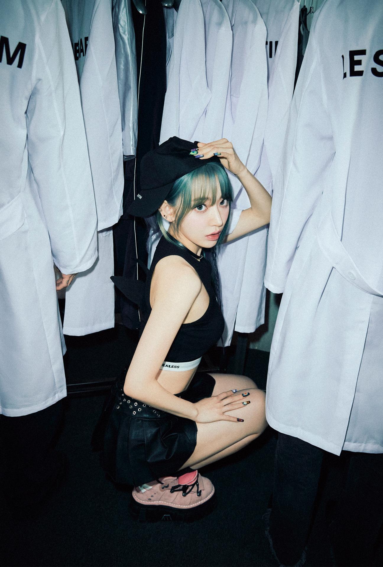 LE SSERAFIM member in a green fuzzy hood, white bralette, and black jacket posing for EASY concept photos