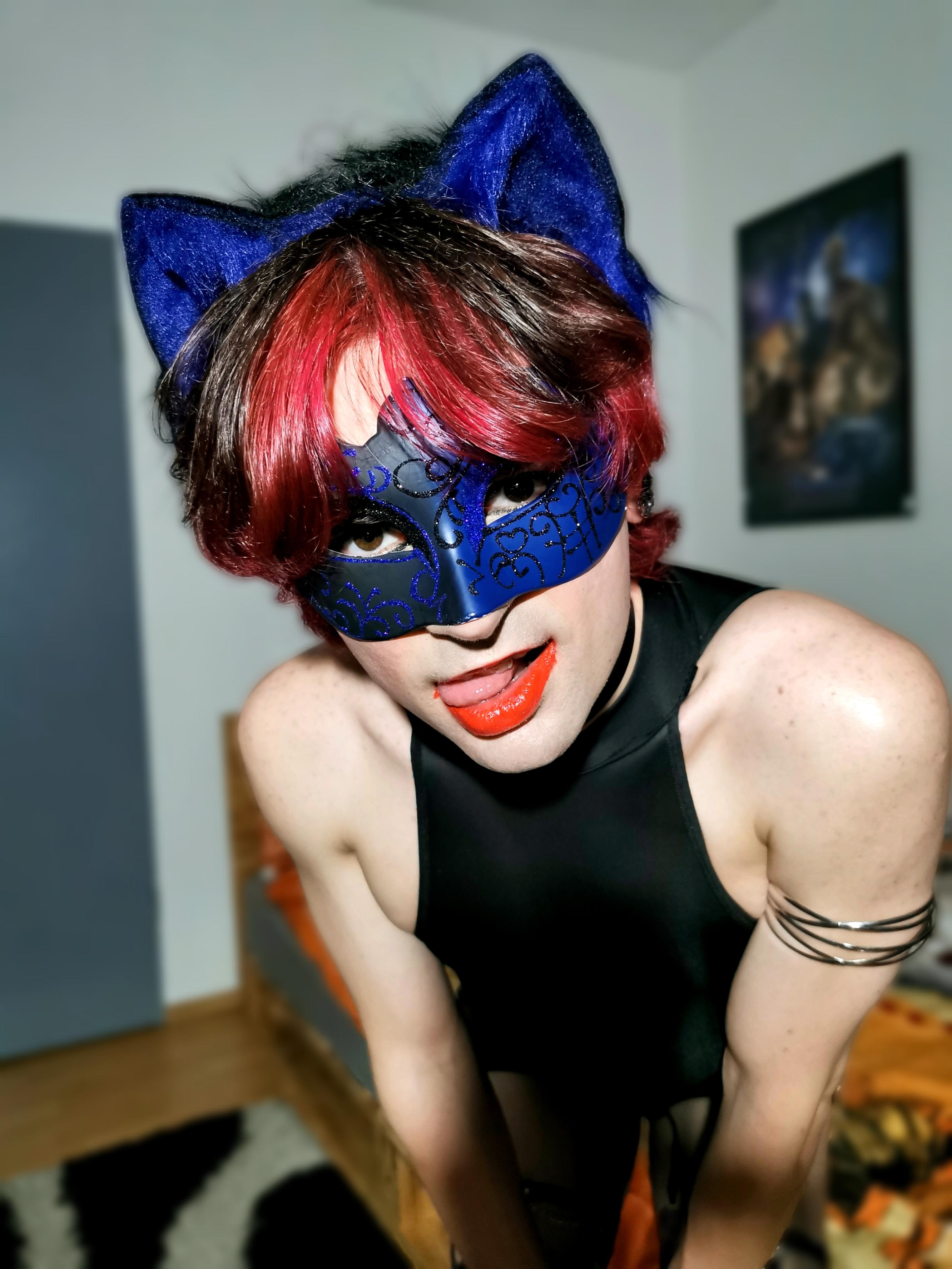 Femboy in a blue catgirl cosplay with a black bodysuit, mask, and cat ears posing for a selfie.