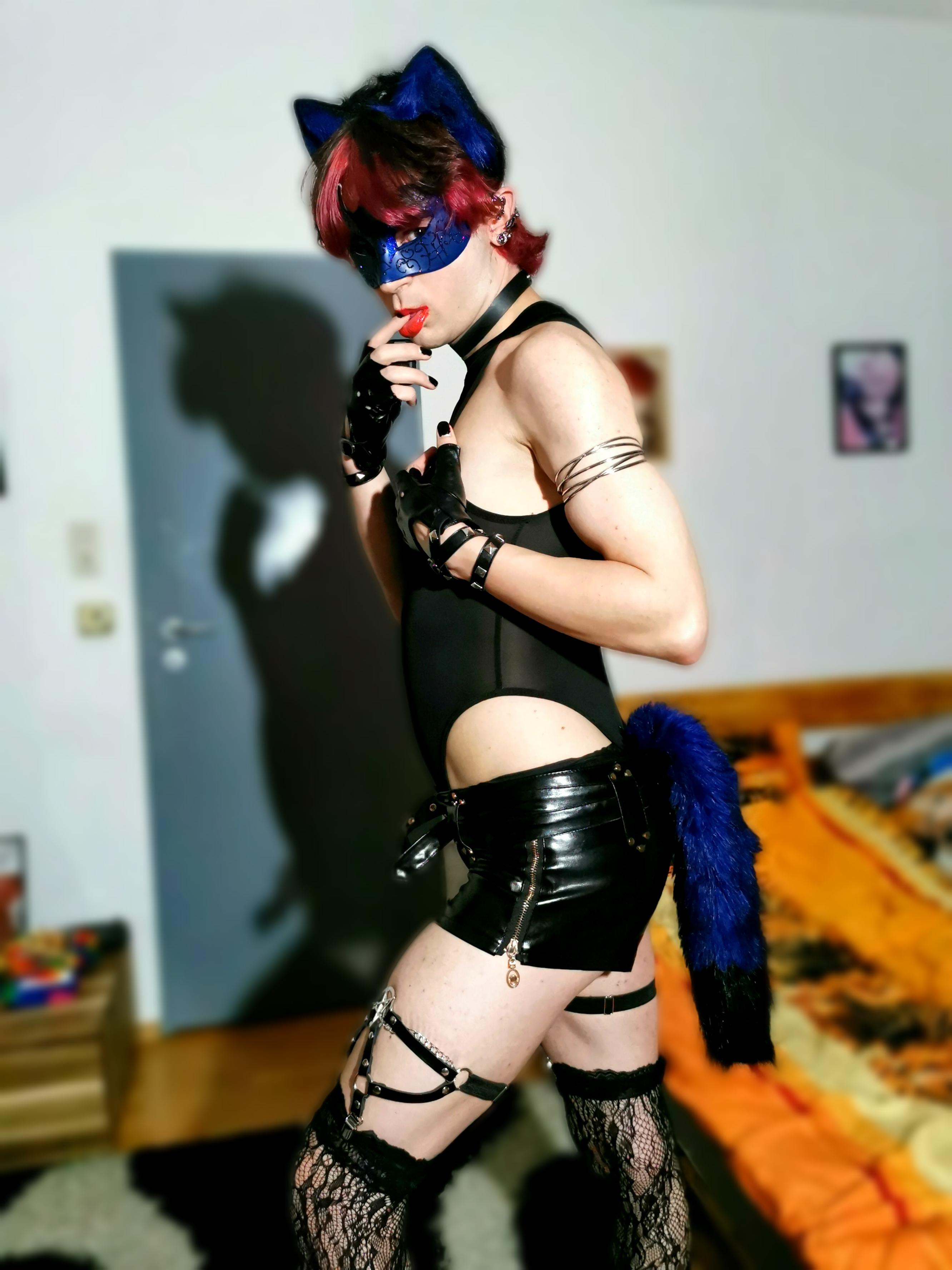 Femboy in a blue catgirl cosplay with a black bodysuit, mask, and cat ears posing for a selfie.