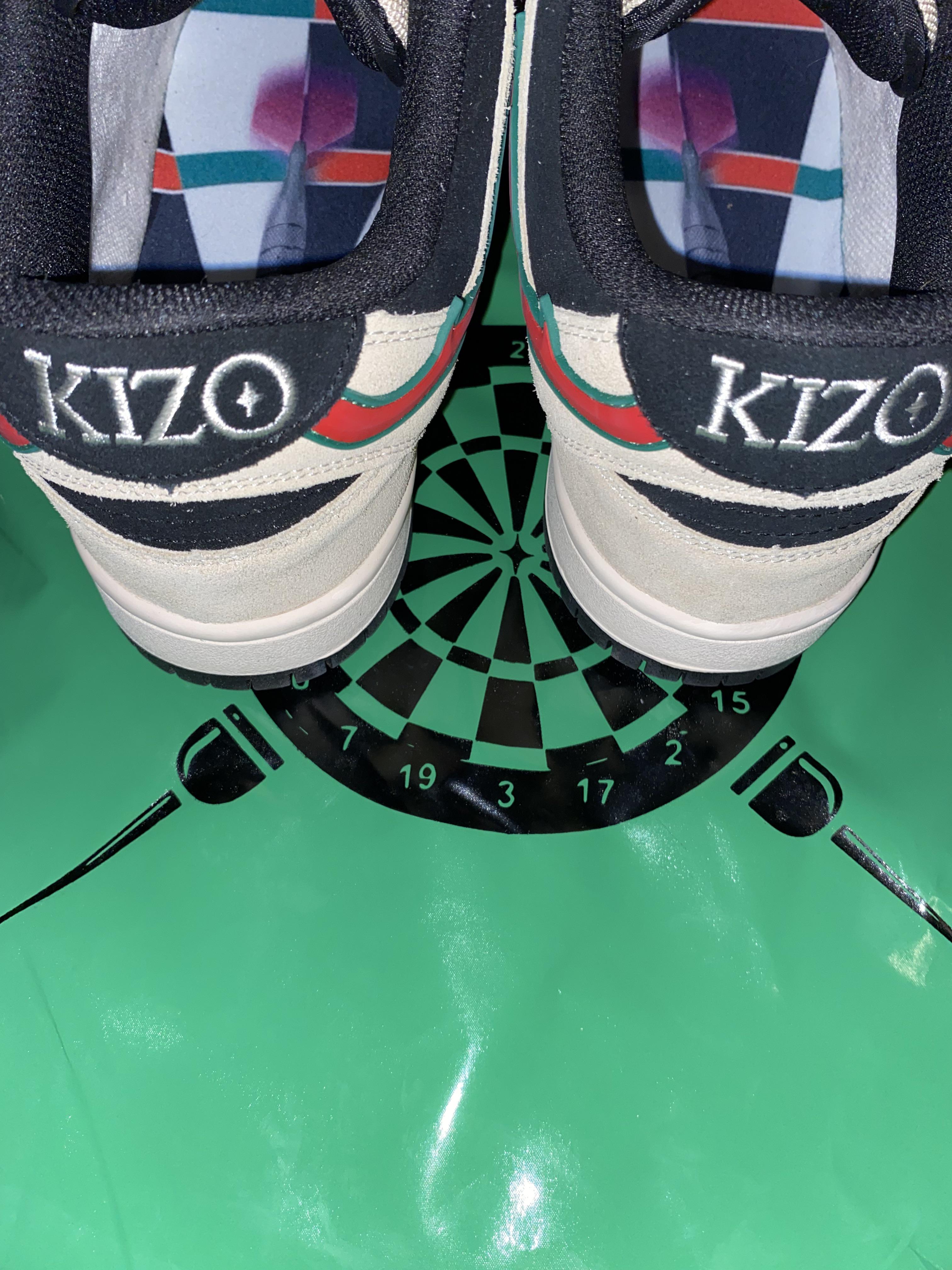 Close-up back view of KIZO sneakers on a green surface with a dartboard graphic.