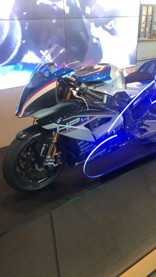 BMW race car and BMW motorcycle on display at BMW Welt with people in the background