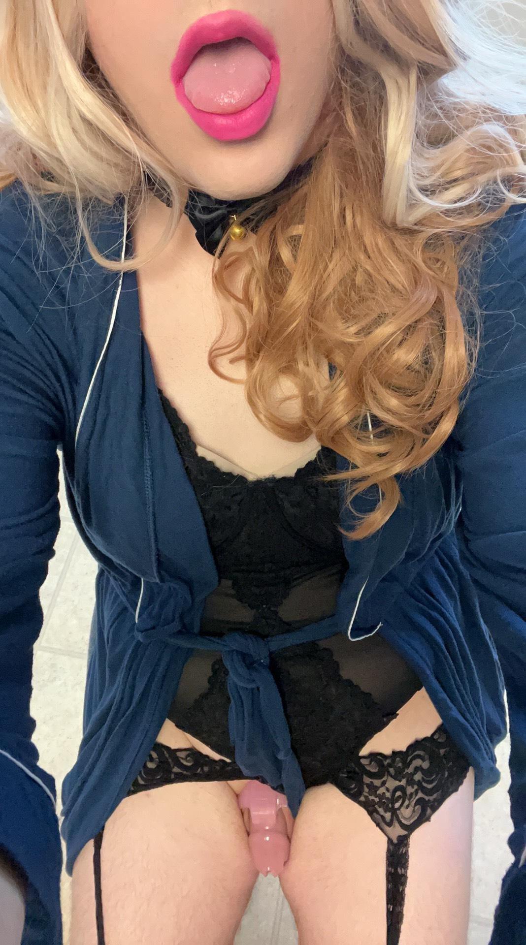 FemPuppyUWU, a curvy blonde trans woman in black lingerie and a choker posing with a huge dildo.