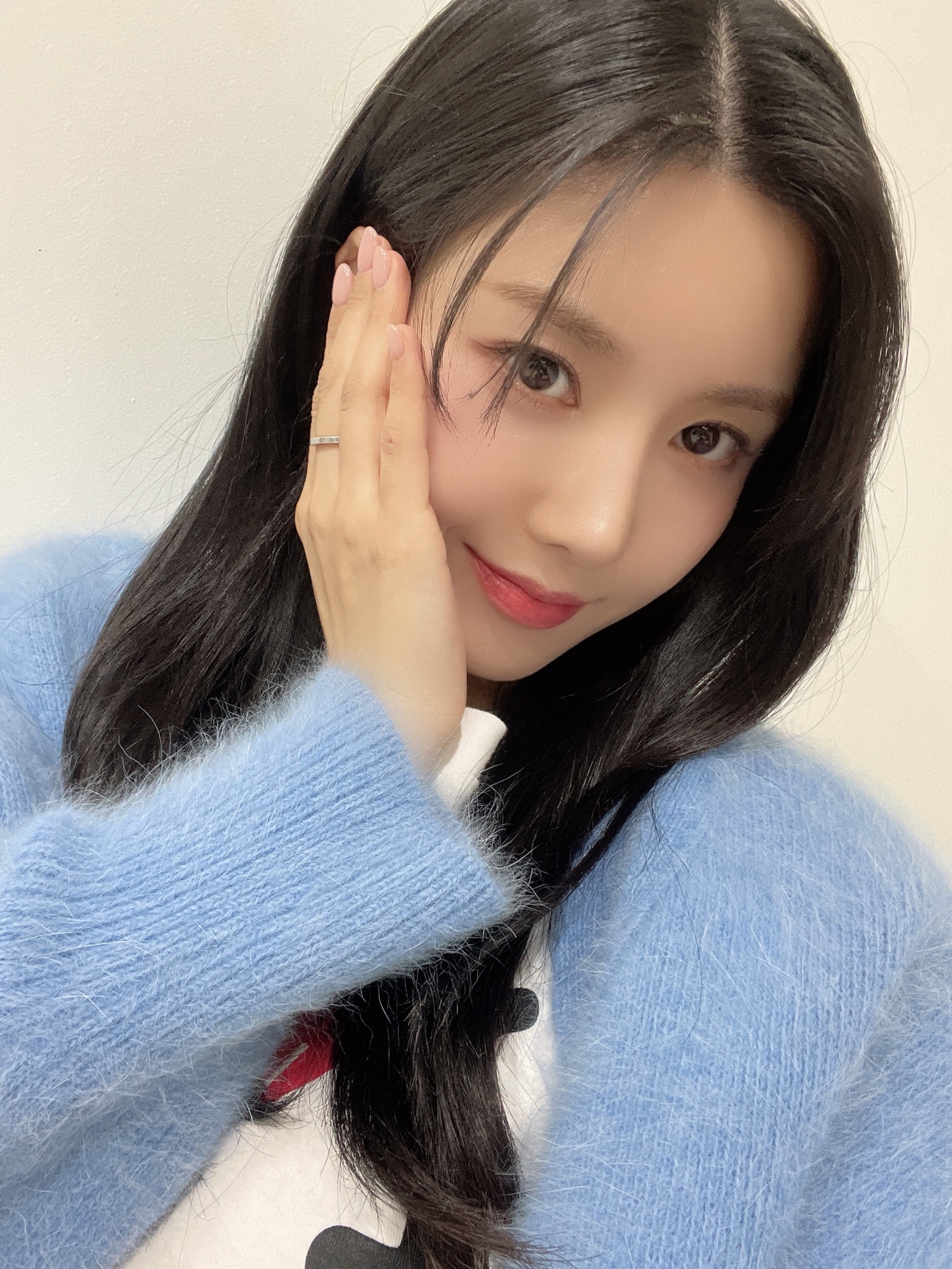 Kwon Eunbi smiling in a blue fuzzy cardigan with her hand on her cheek