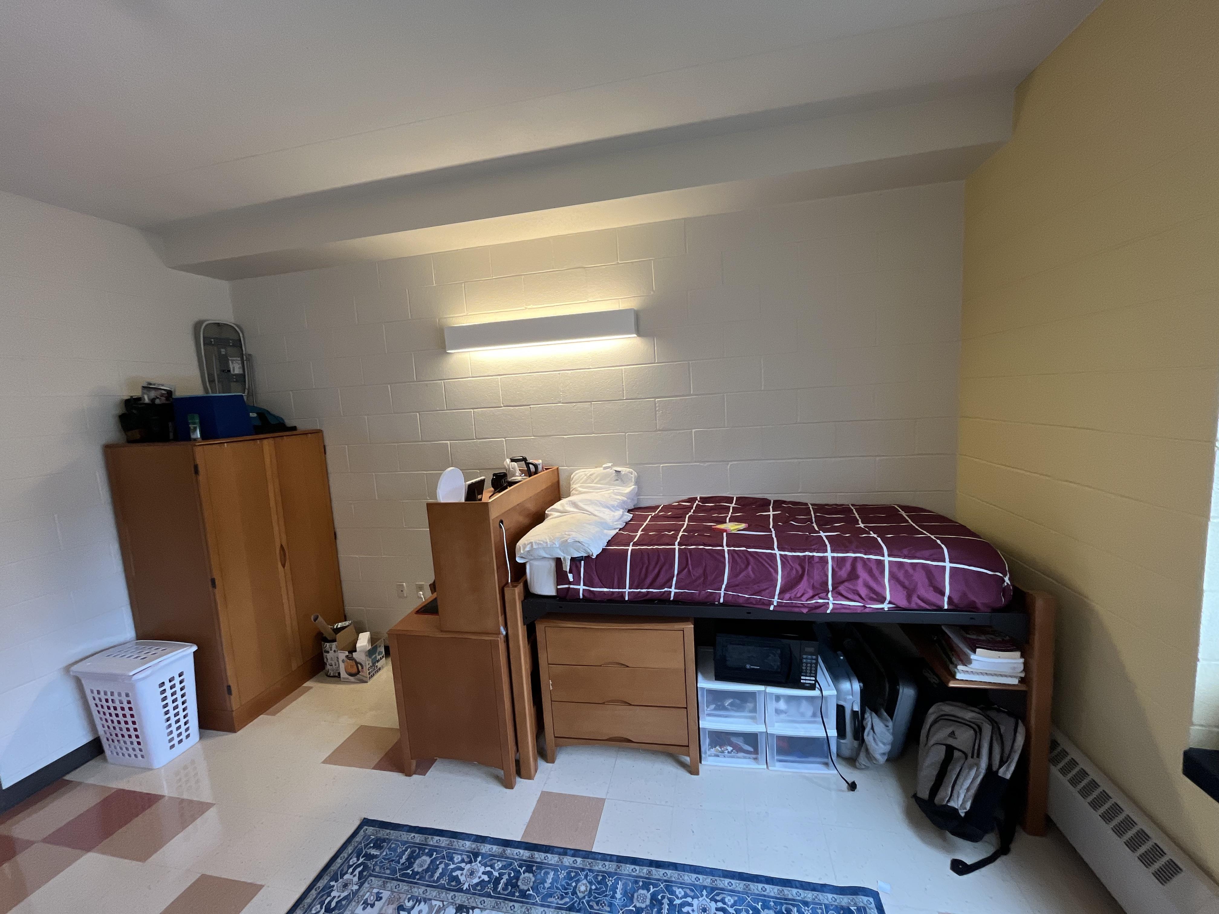 2nd year college dorm room with beds, desks, a wardrobe, and a blue rug